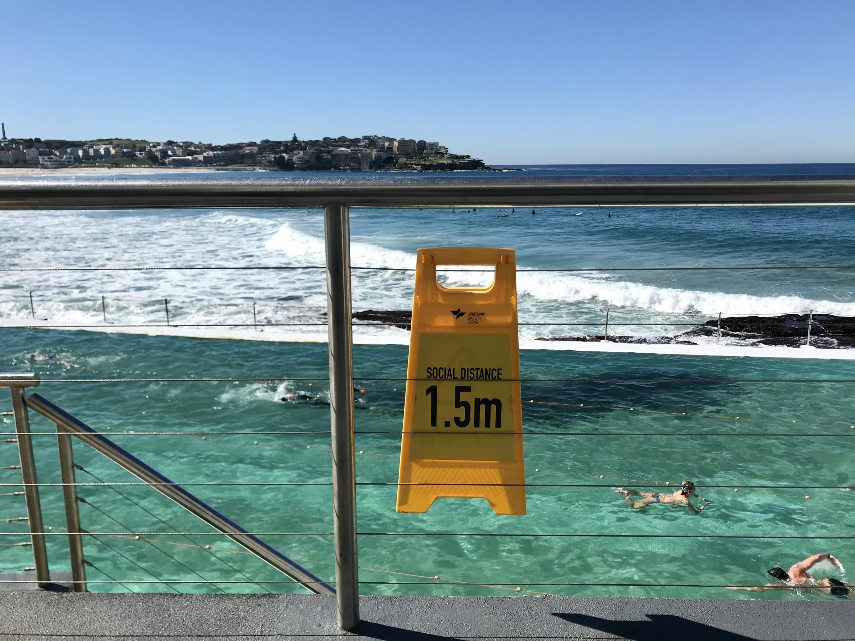 Im Meeresschwimmbad 'Icebergs' in Sydneys Strandvorort Bondi Beach ziehen Krauler ihre Bahnen. Ein Schild erinnert daran, 1,5 Meter Abstand zu anderen Menschen zu halten. In der letzten Juniwoche geht auch das Meeresschwimmbad wieder in den Lockdown.