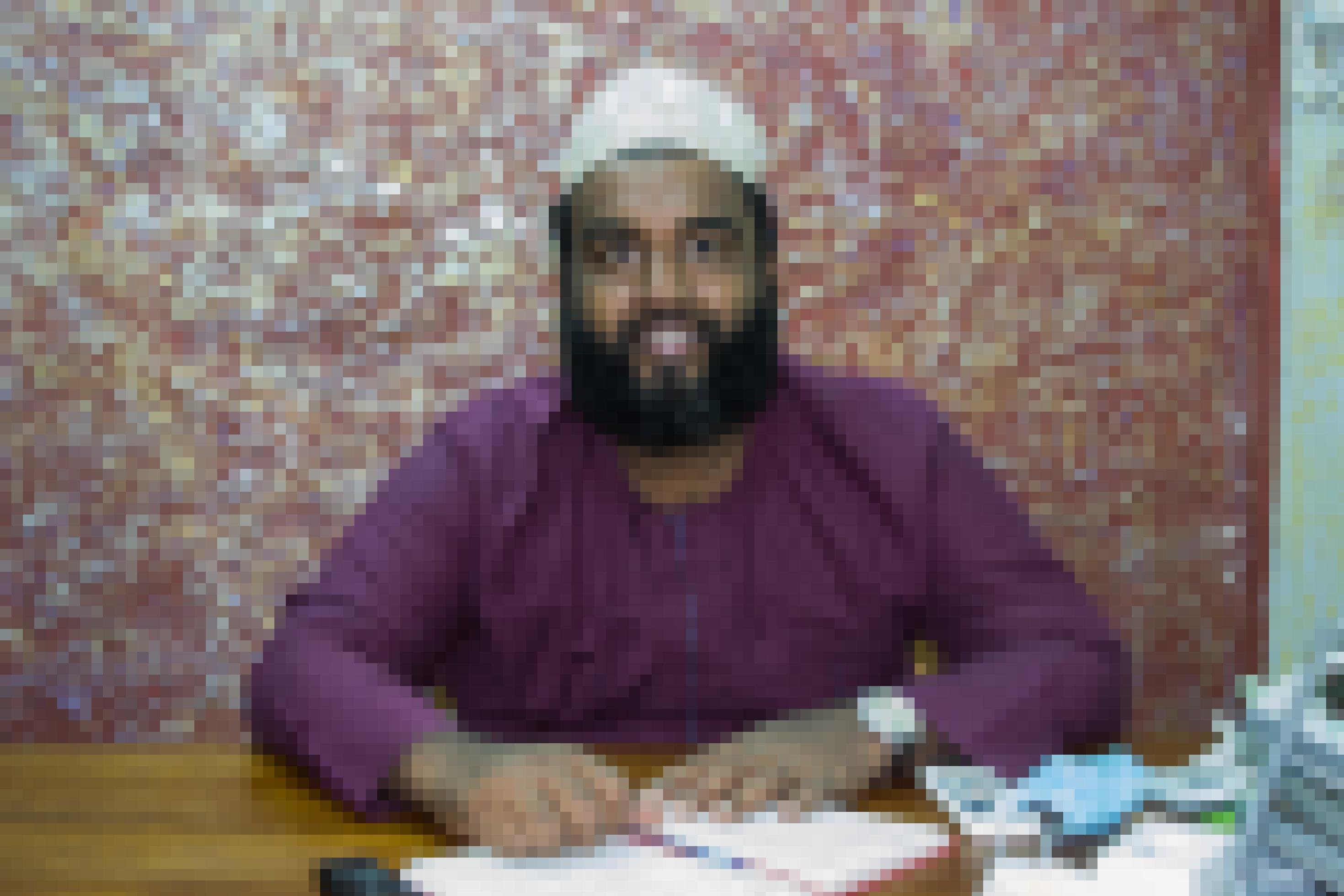 Das Foto zeigt Abulrahman Taib in seinem Büro. Er ist Direktor der Organisation „REachout“. Er trägt eine Kopfbedeckung und ein violettes, muslimisches Gewand.