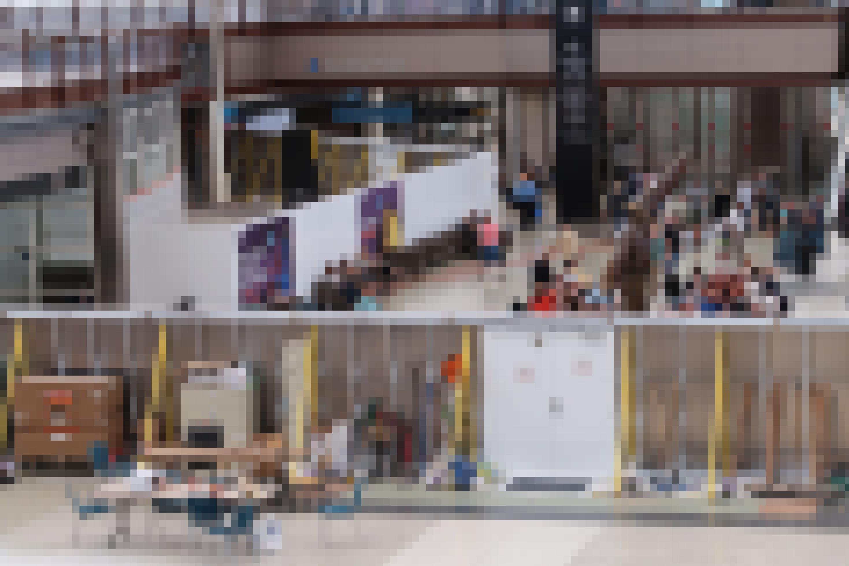 Das Bild zeigt Personen im Wartebereich eines Terminals. Im Terminal sind Sichtschutzwände mit Plakatmotiven aufgestellt. Dahinter sieht man eine Baustelle.
