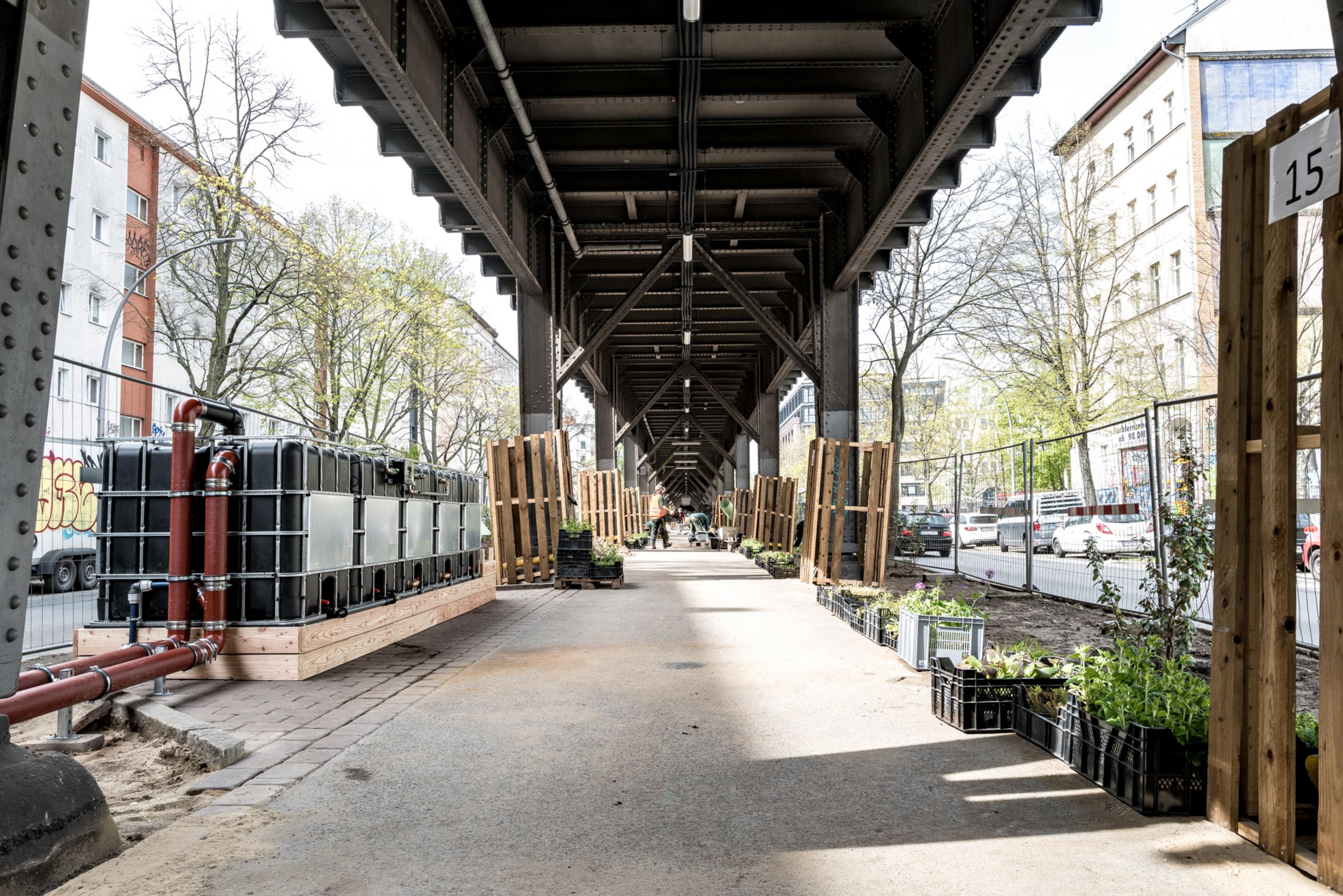 Pflanzen und Wassertanks stehen unter dem Viadukt der Hochbahn.