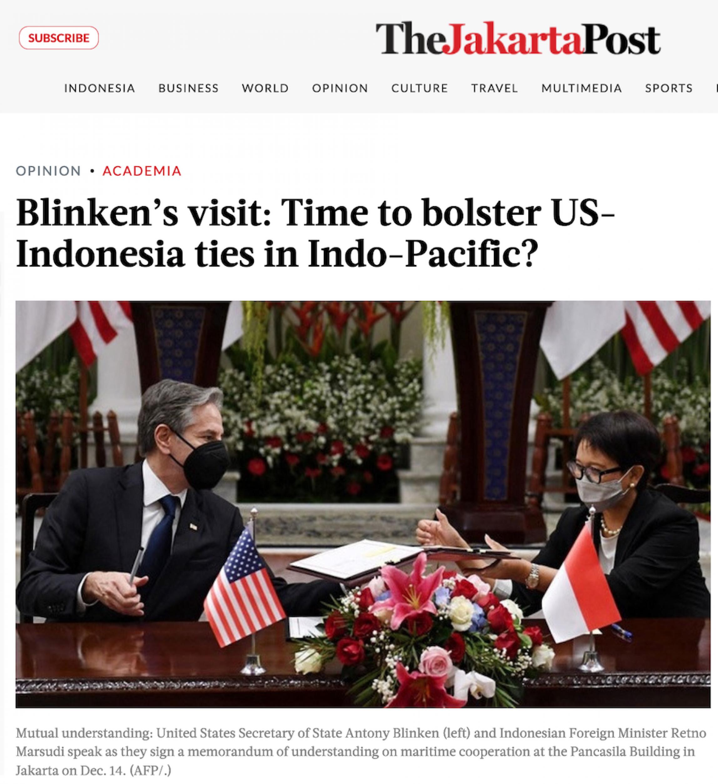 US-Außenminister Antony Blinken und seine indonesische Kollegin Retno Marsudi sitzen beim Treffen im Dezember 2021 an einem Holztisch, der mit kleinen Nationalfahnen ihrer Länder geschmückt ist