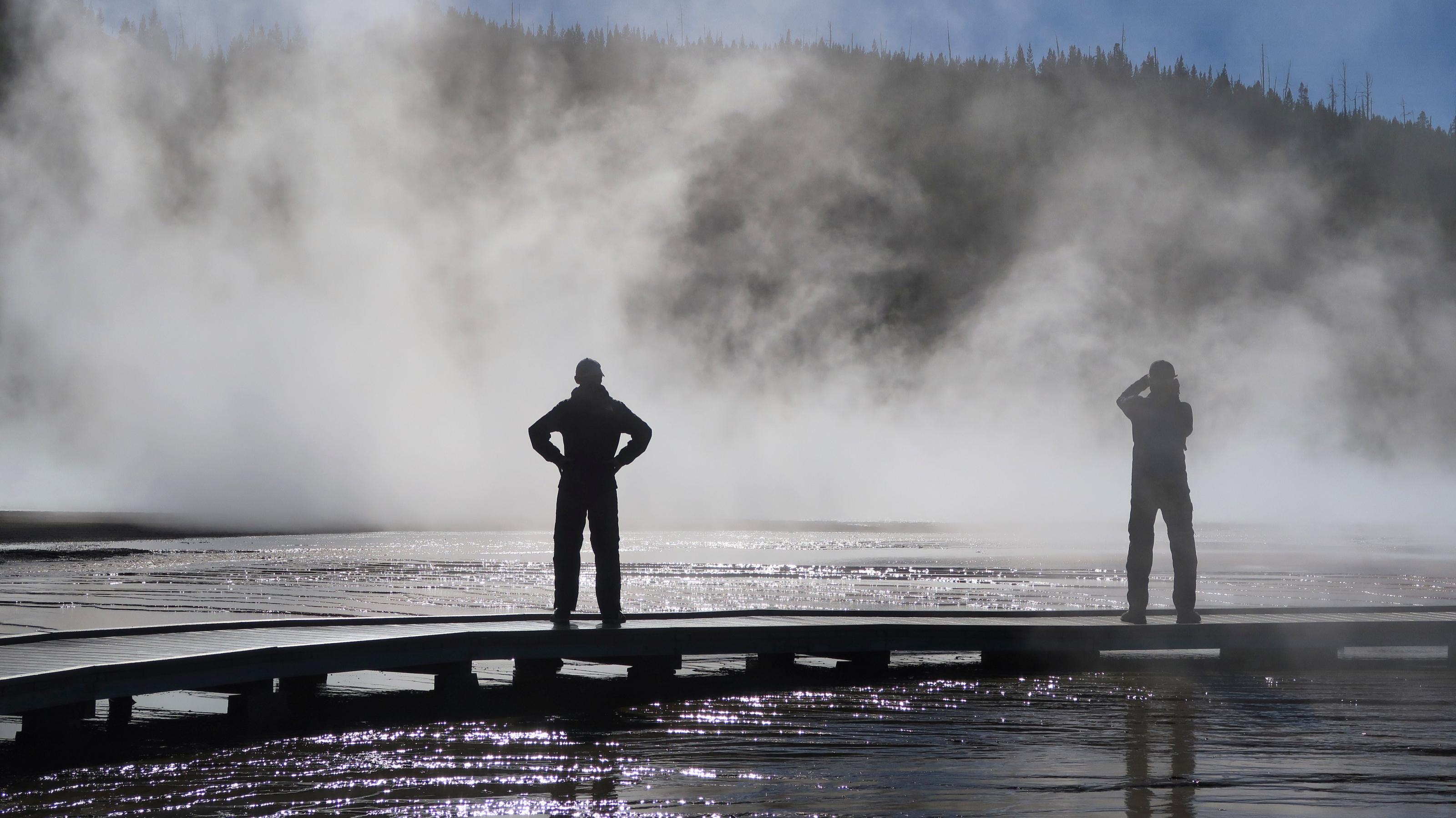 Ein Mann steht im Gegenlicht vor einer dampfenden Quelle