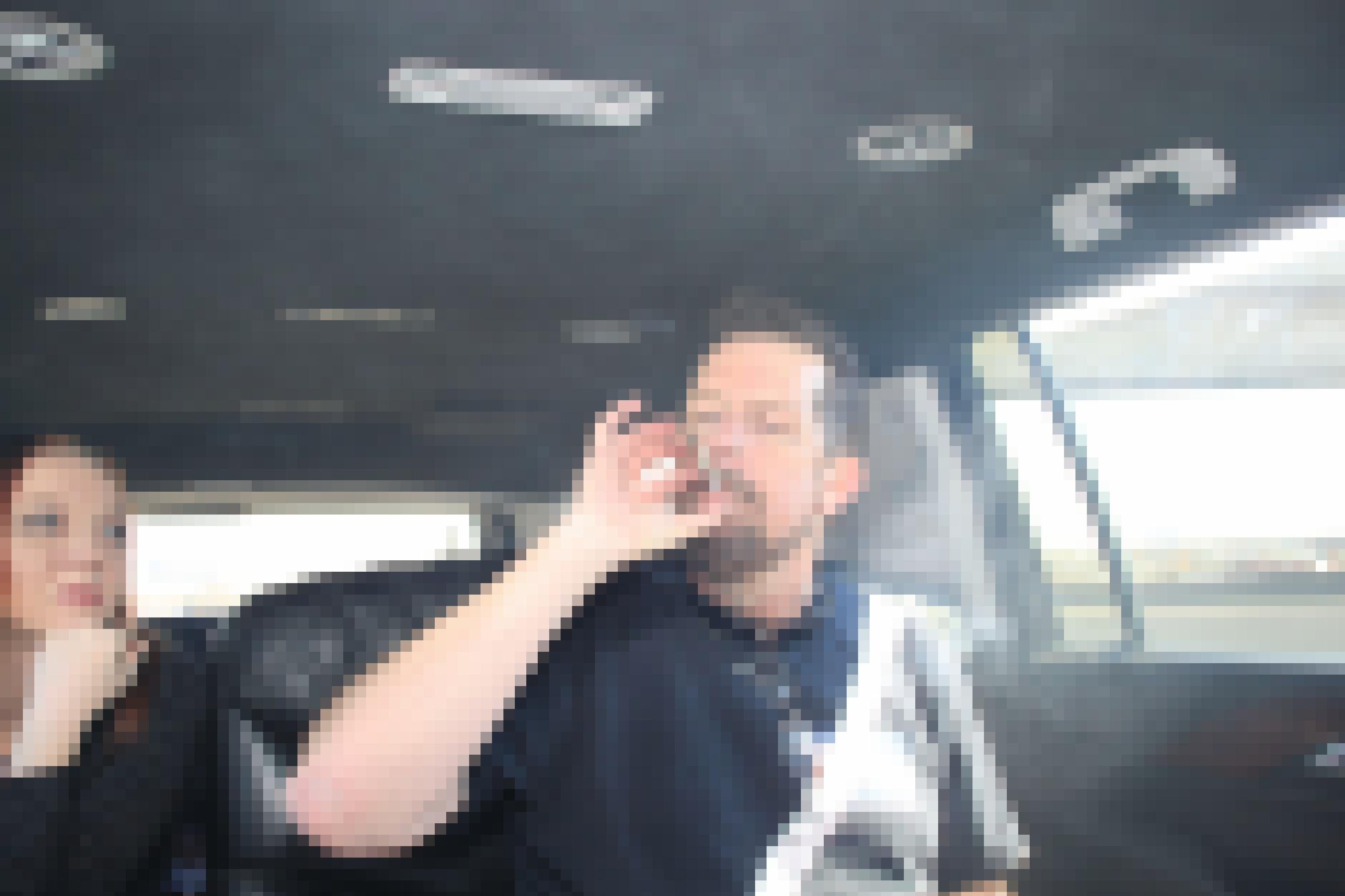 Ein Mann mittleren Alters zieht in einem Auto an einem Joint.
