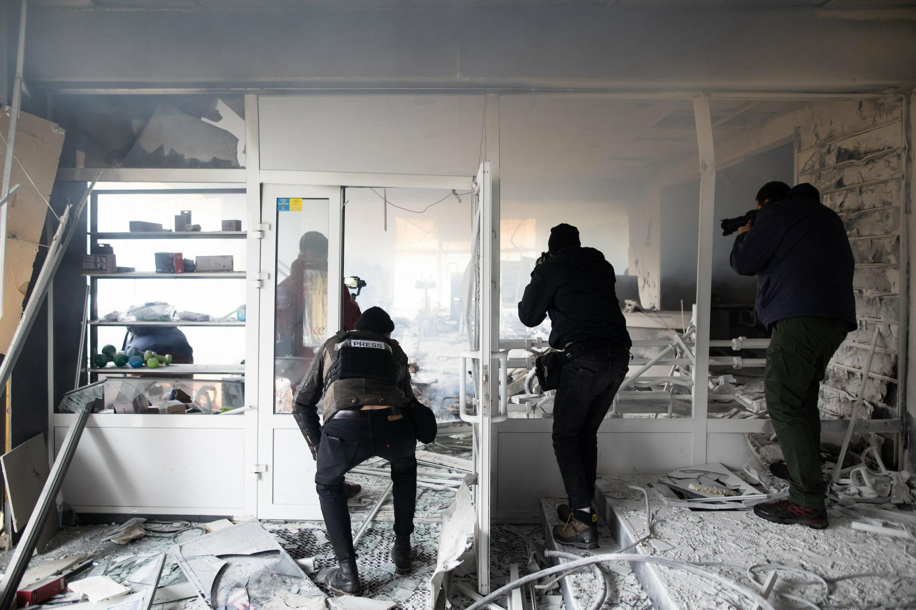 Reporter in Schutzhelmen und kugelsicheren Westen dokumentieren die Zerstörung eines Hauses in Kiew nach russischen Angriffen am 2. März 2022.