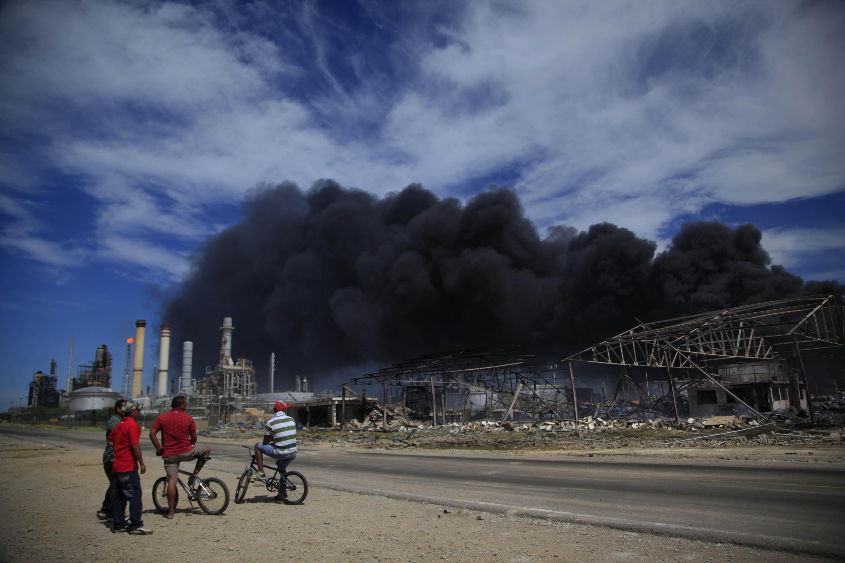 Eine Gruppe von Männern beobachtet, wie schwarzer Rauch weiterhin aus der Amuay-Raffinerie in der Nähe von Punto Fijo, Venezuela, aufsteigt.