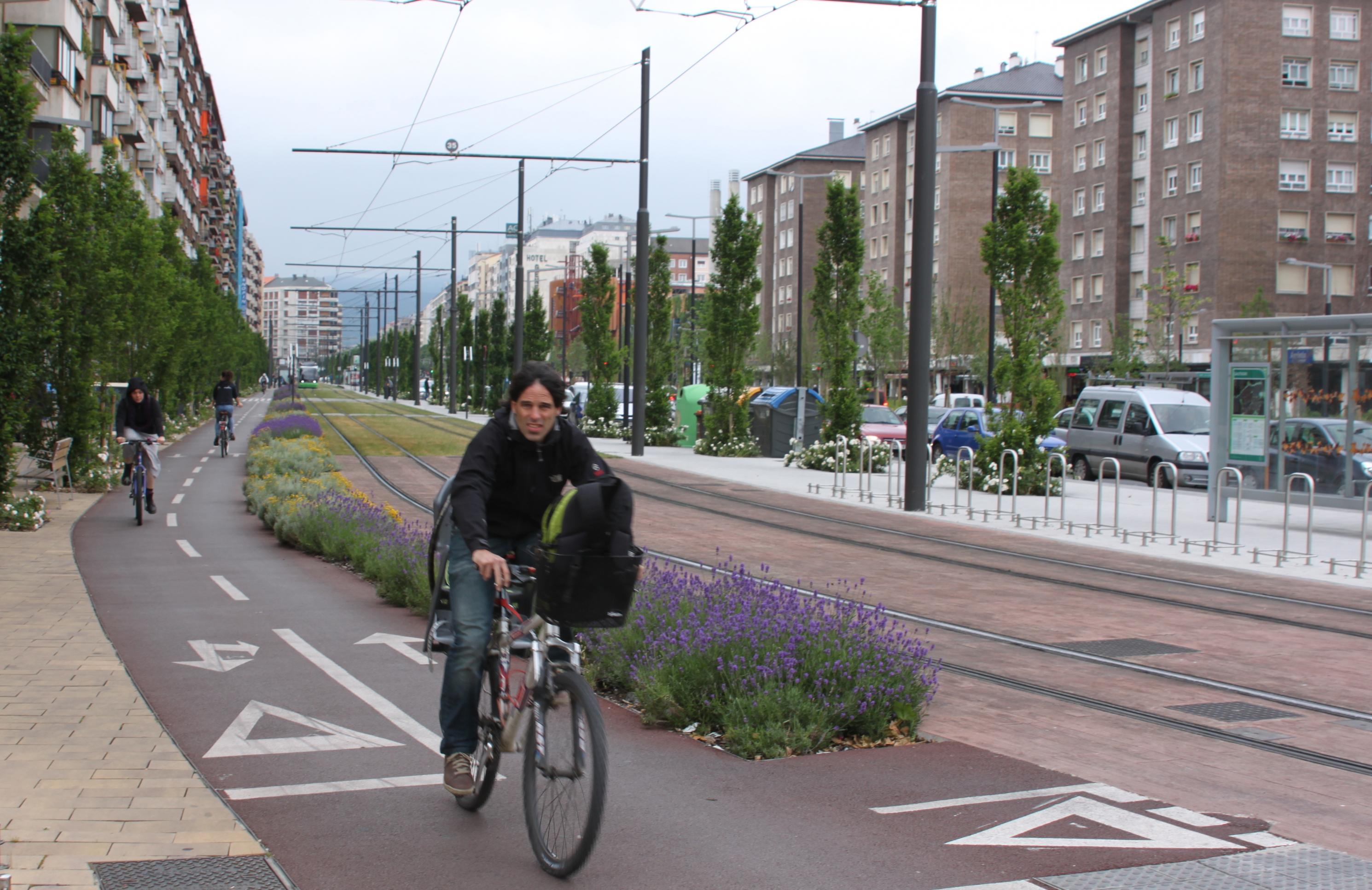 Eine Radfahrerin fährt auf einer Radspur neben Tramschienen. Hochhäuser sind an beiden Straßenseiten zu sehen.