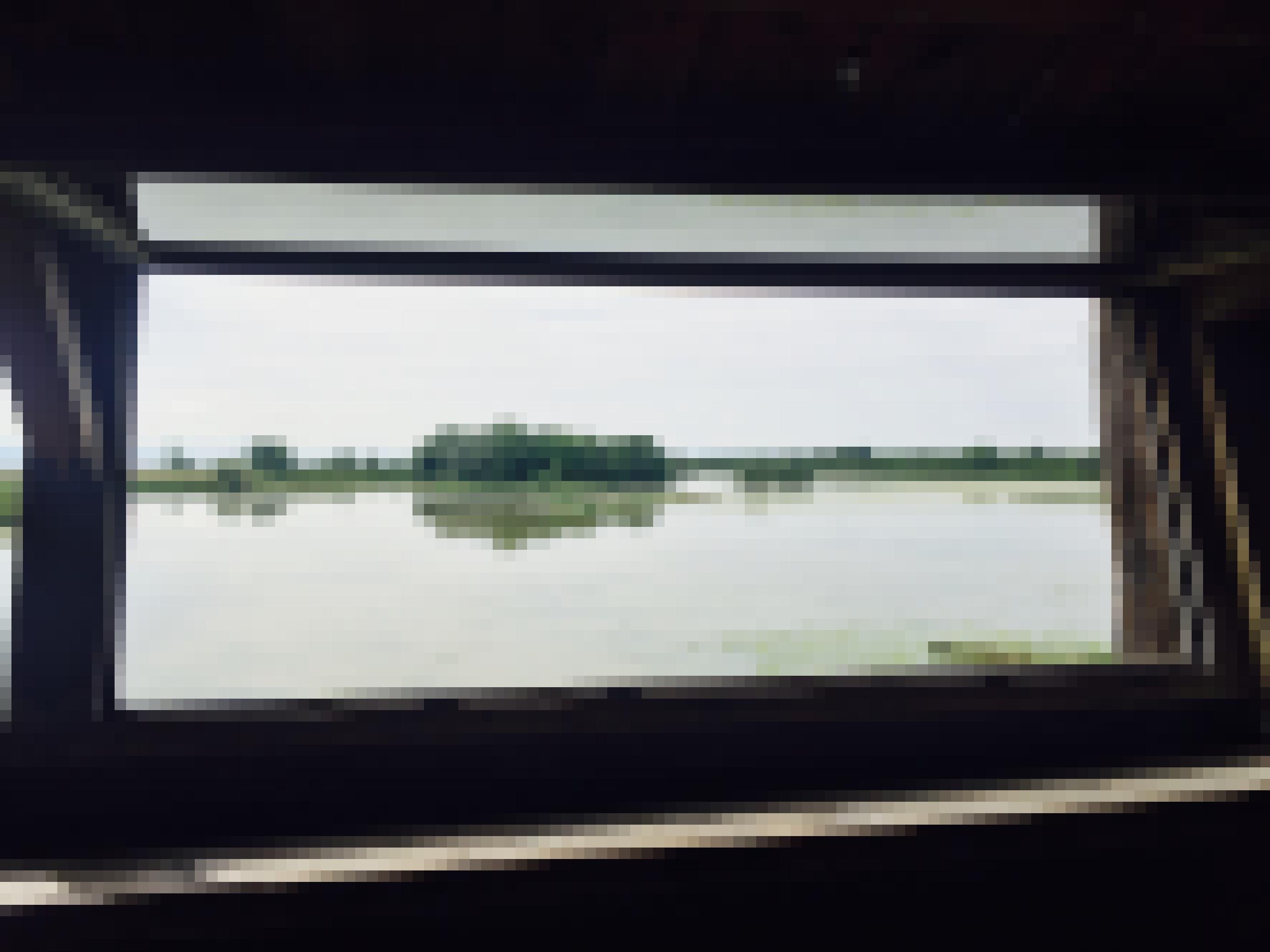 Blick durch die Luke einer Beobachungshütte an der Mündung des Flusses Isonozo in Italien. Man sieht direkt davor eine Gruppe von Krähenscharben im Wasser paddeln.