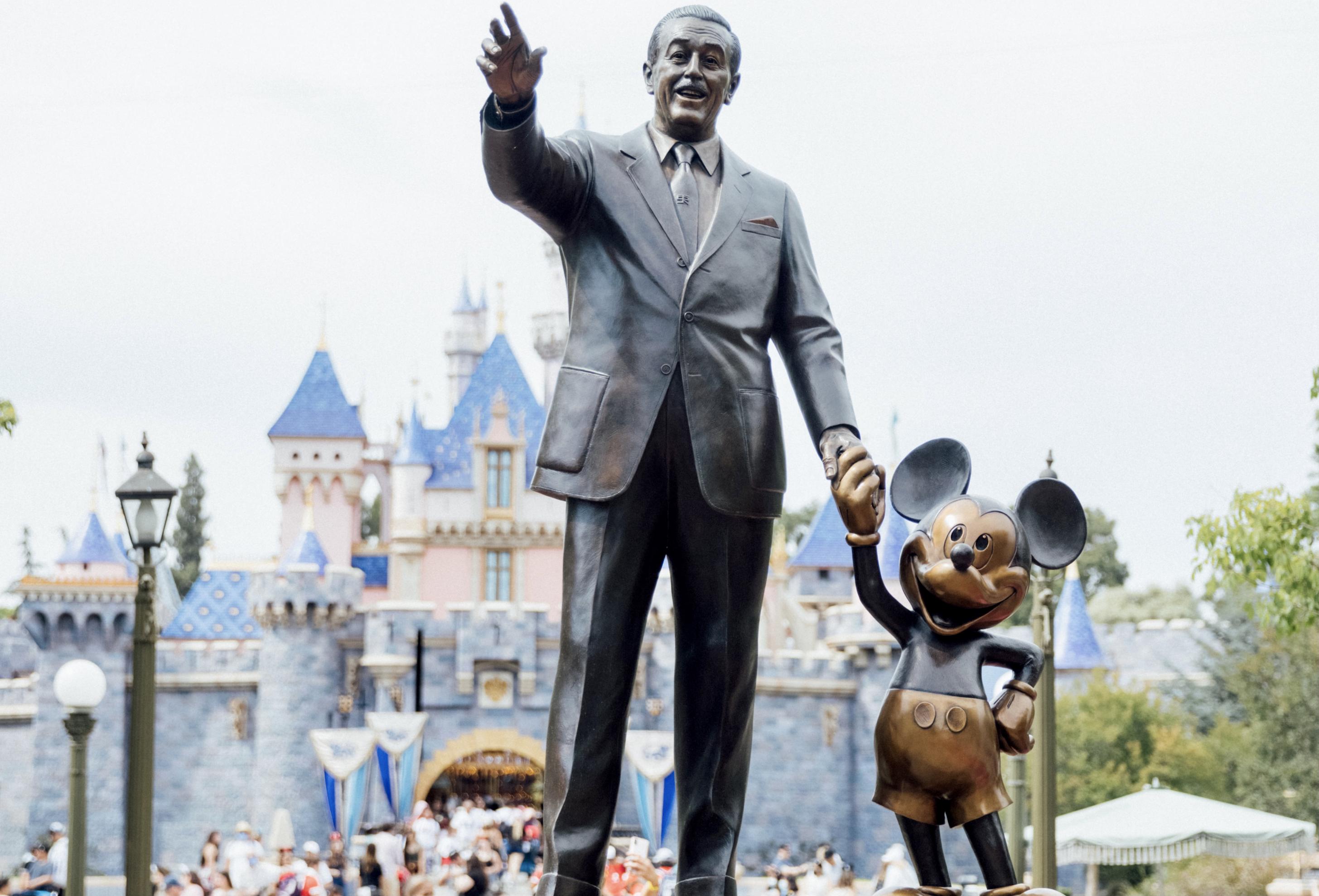 Bronzestatue von Walt Disney und Mickey Mouse Händchen haltend am Eingang von Disneyland, Walt Disney scheint auf die Besucher zuzugehen, Mickey hält eine Hand in die Hüfte.
