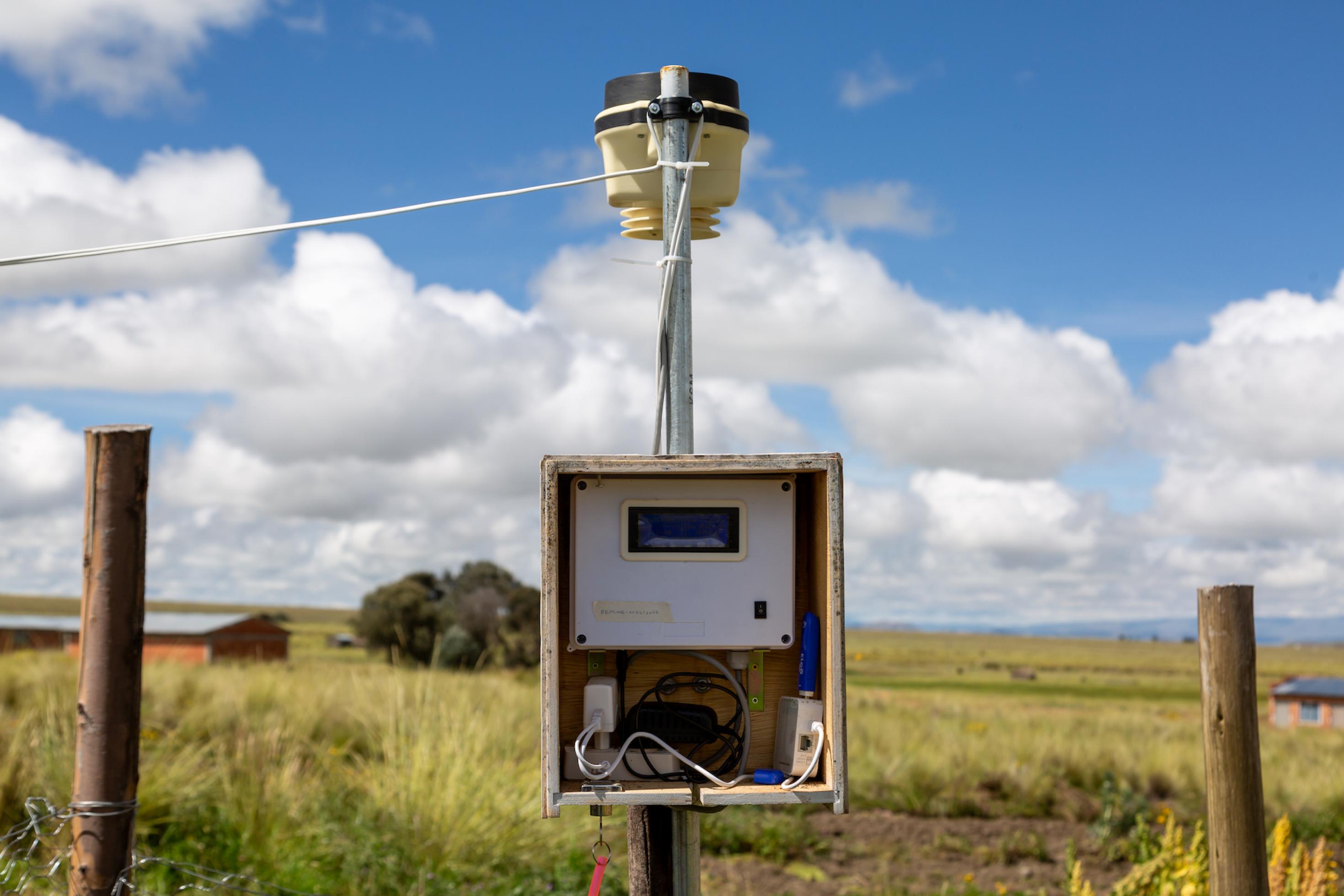 Eine kleine mobile Wetterstationen vor blauem Himmel in einer ländlichen Region. Stationen wie diese sollen den Andenbewohnerïnnen helfen sich an den Klimawandel anzupassen.