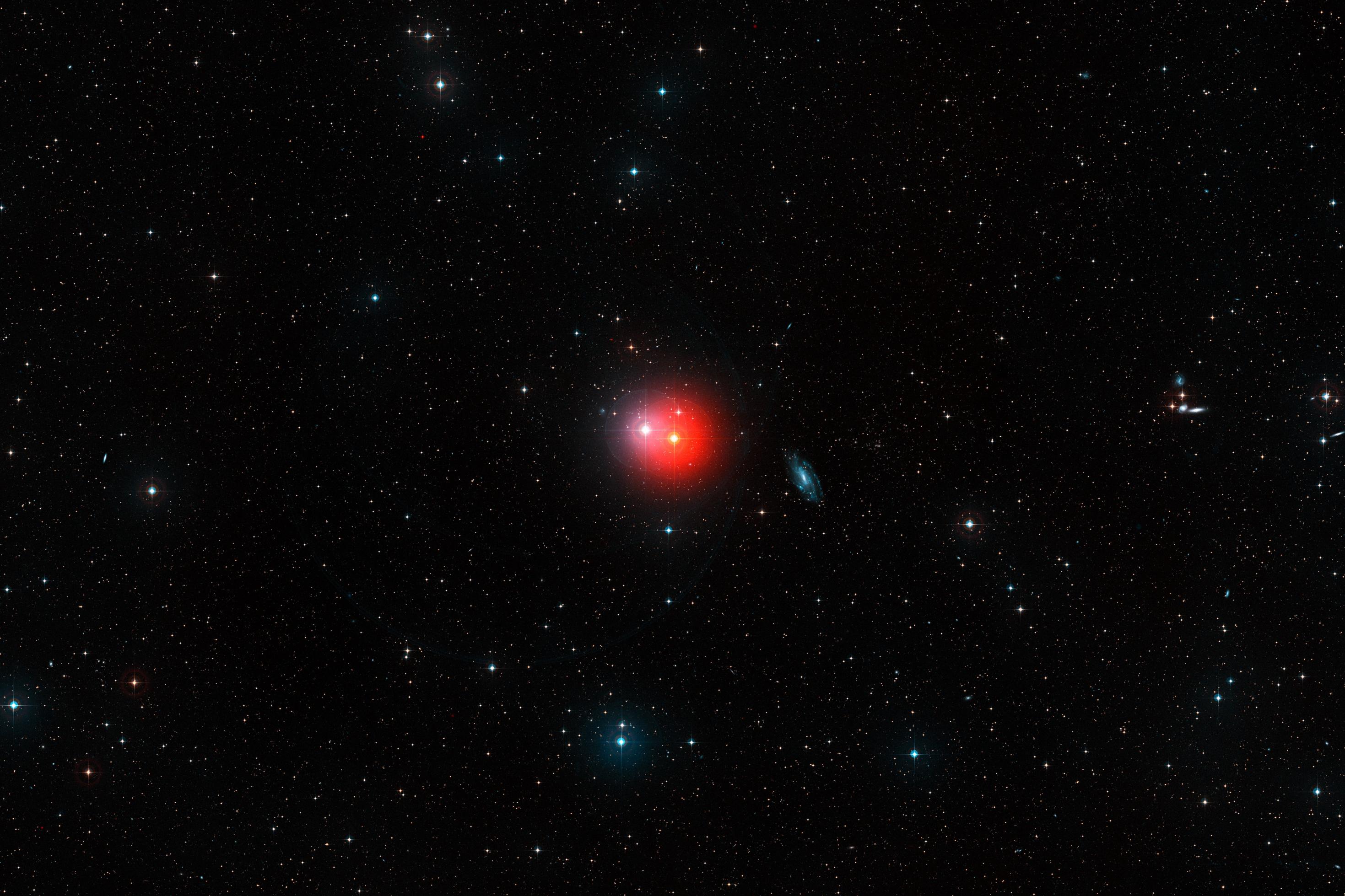 This colourful image shows the sky around the bright pair of stars ?1 Gruis (centre-right, very red) and ?2 Gruis (centre-left, bluish-white). Just right of centre the bright spiral galaxy IC 5201 is also visible and many other fainter galaxies are scattered across this wide-field image from the Digitized Sky Survey 2.