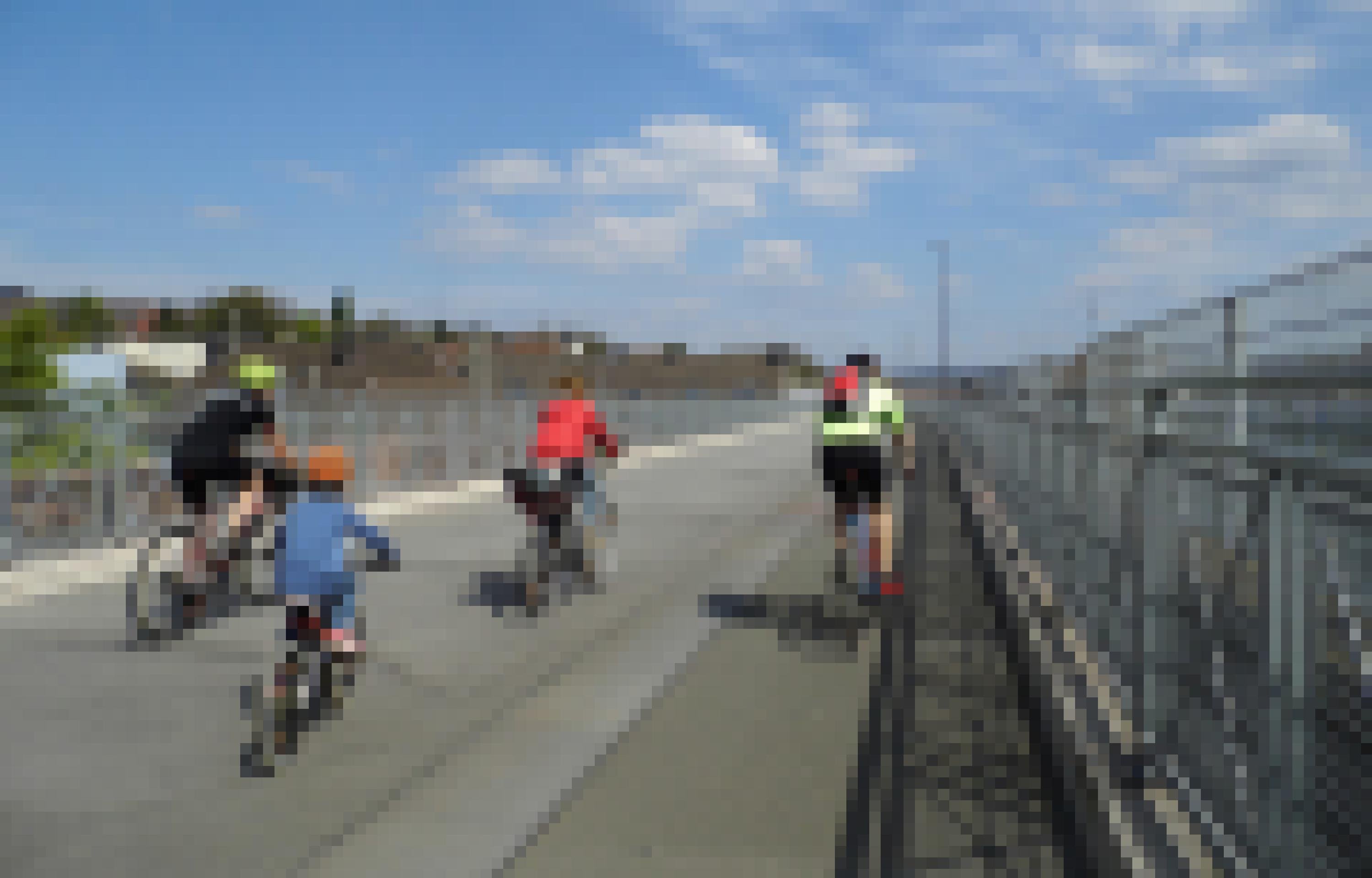 Vier junge Personen fahren unter blauem Himmel mit ihrem Rad über die Brücke.