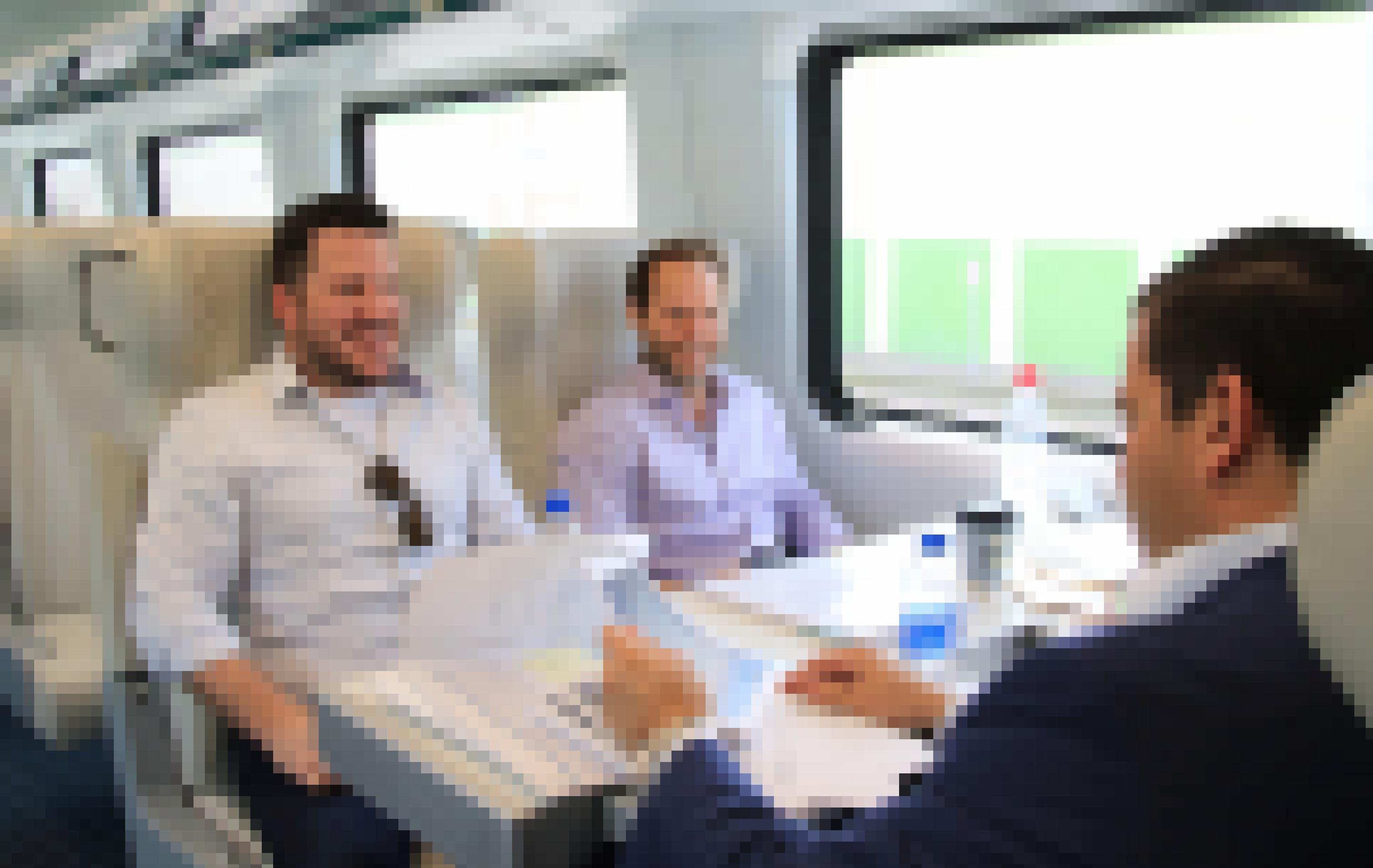 Drei Männer sitzen im Zug an einem Tisch.