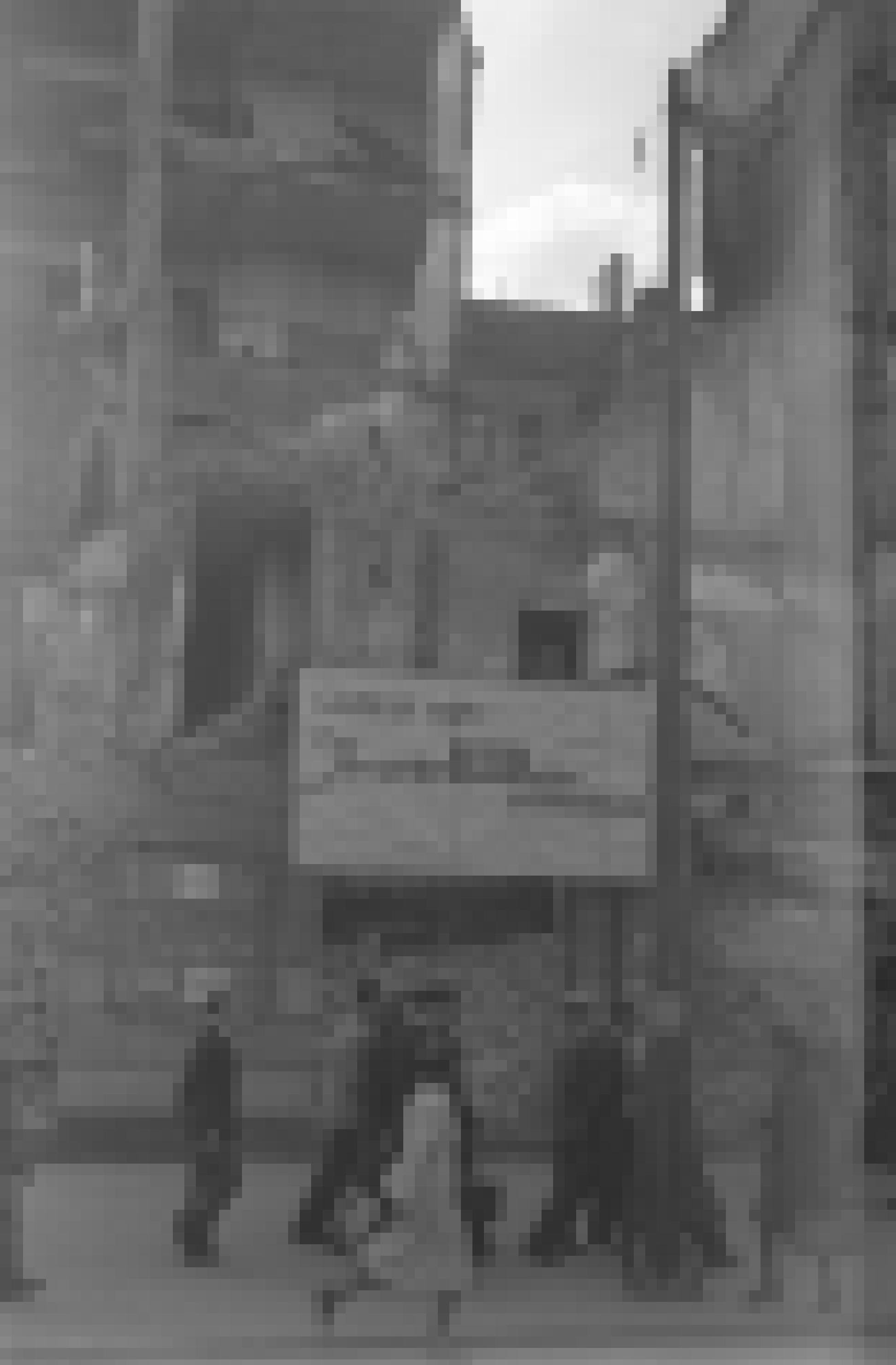 Schwarz-Weiß-Foto mit Passantin, die an Trümmerhaufen vorbeiläuft. Zu sehen ist ein Schild mit einem Zitat von Goebbels: „Ihr werdet Berlin nicht wiedererkennen.“