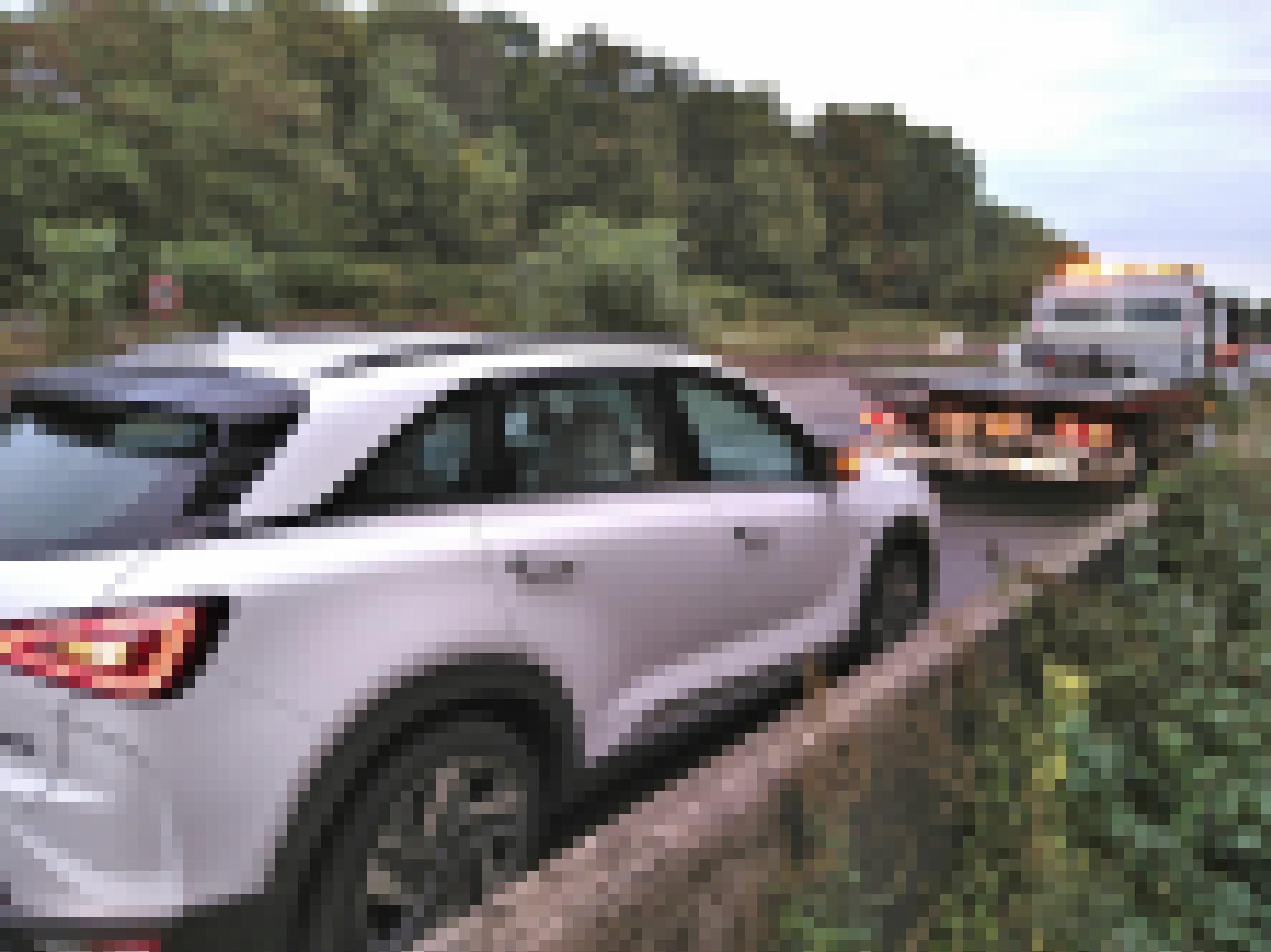 Ein Abschleppwagen steht vor einem Auto auf dem Standstreifen der Autobahn.