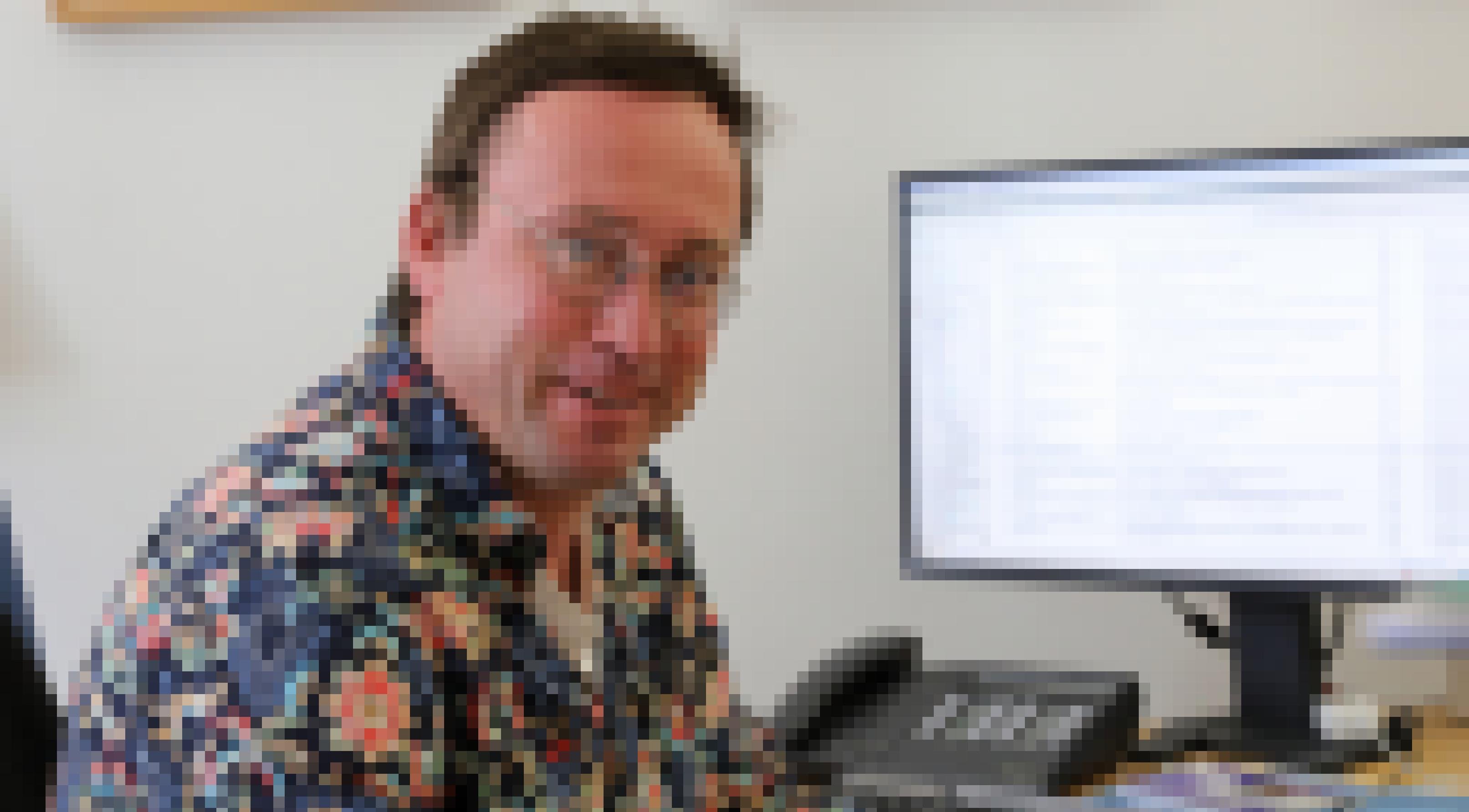 Nabu-Bundesgeschäftsführer Leif Miller sitzt hinter seinem Computer in einem bunten Hemd