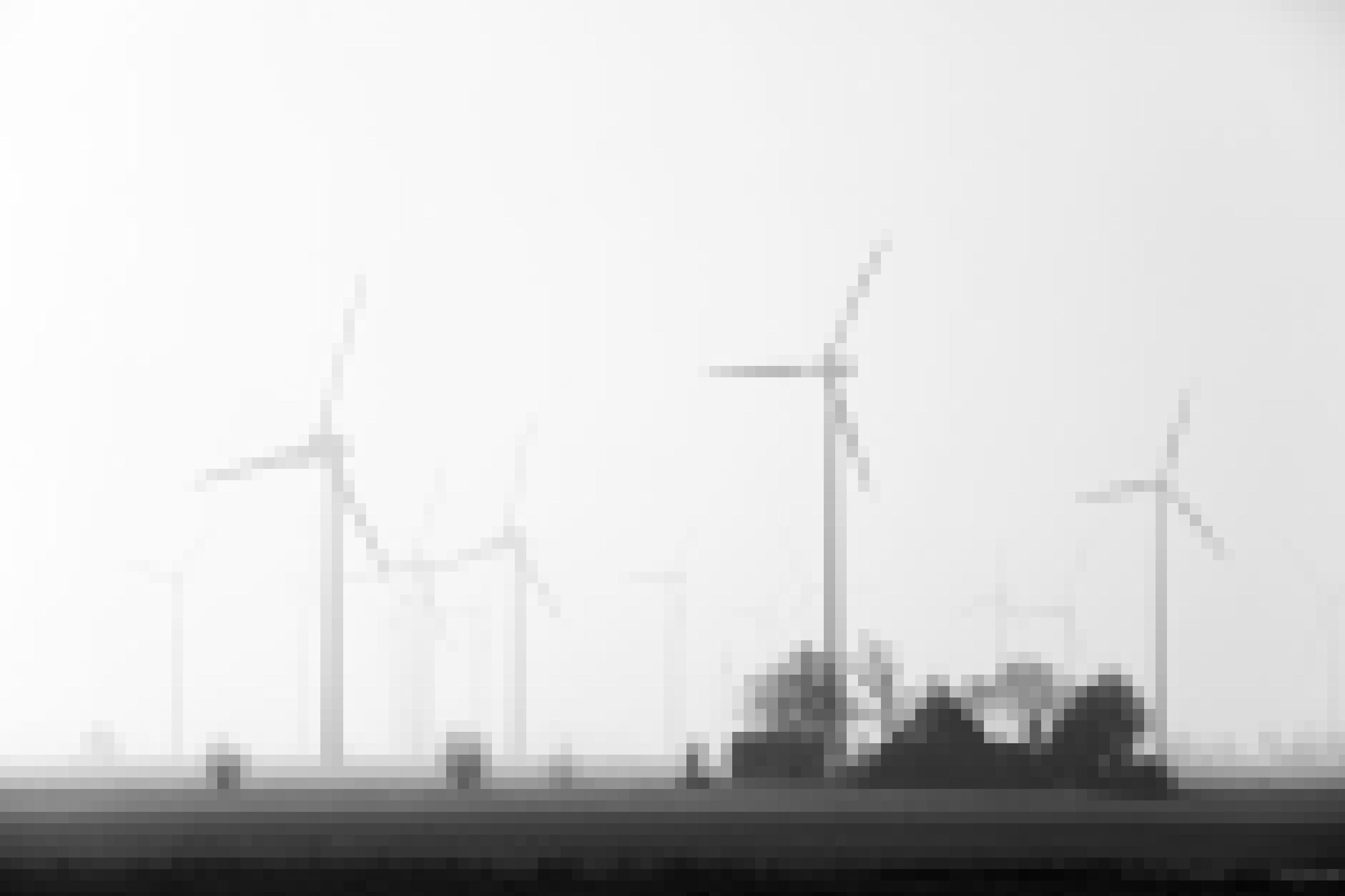 Eine Gruppe von Windenergieanlagen in der flachen norddeutschen Landschaft, im Vordergrund reetgedeckte Bauernhäuser.