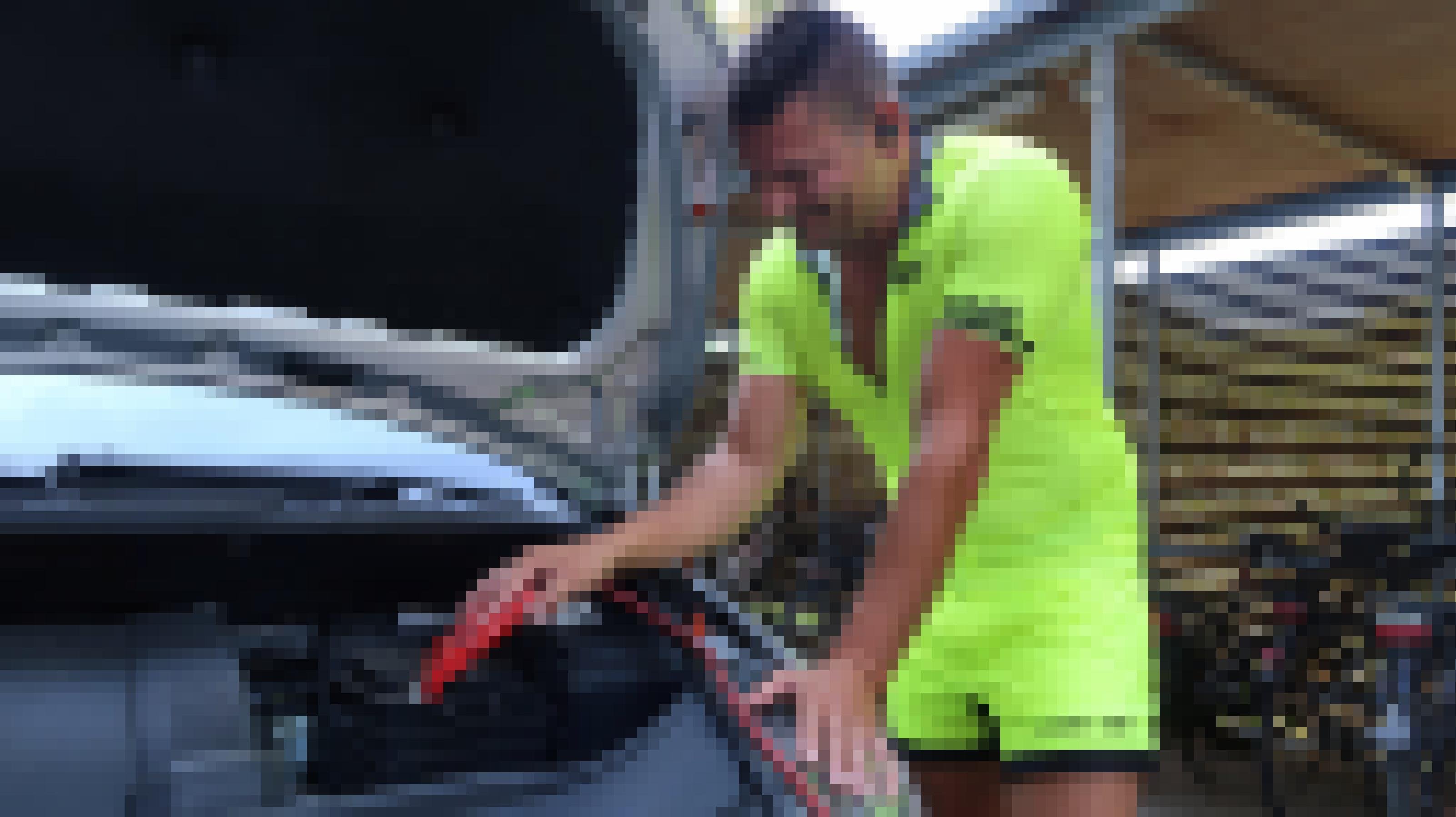 Ein ADAC-Pannenhelfer befestigt ein Starterkabel an einer Autobatterie.