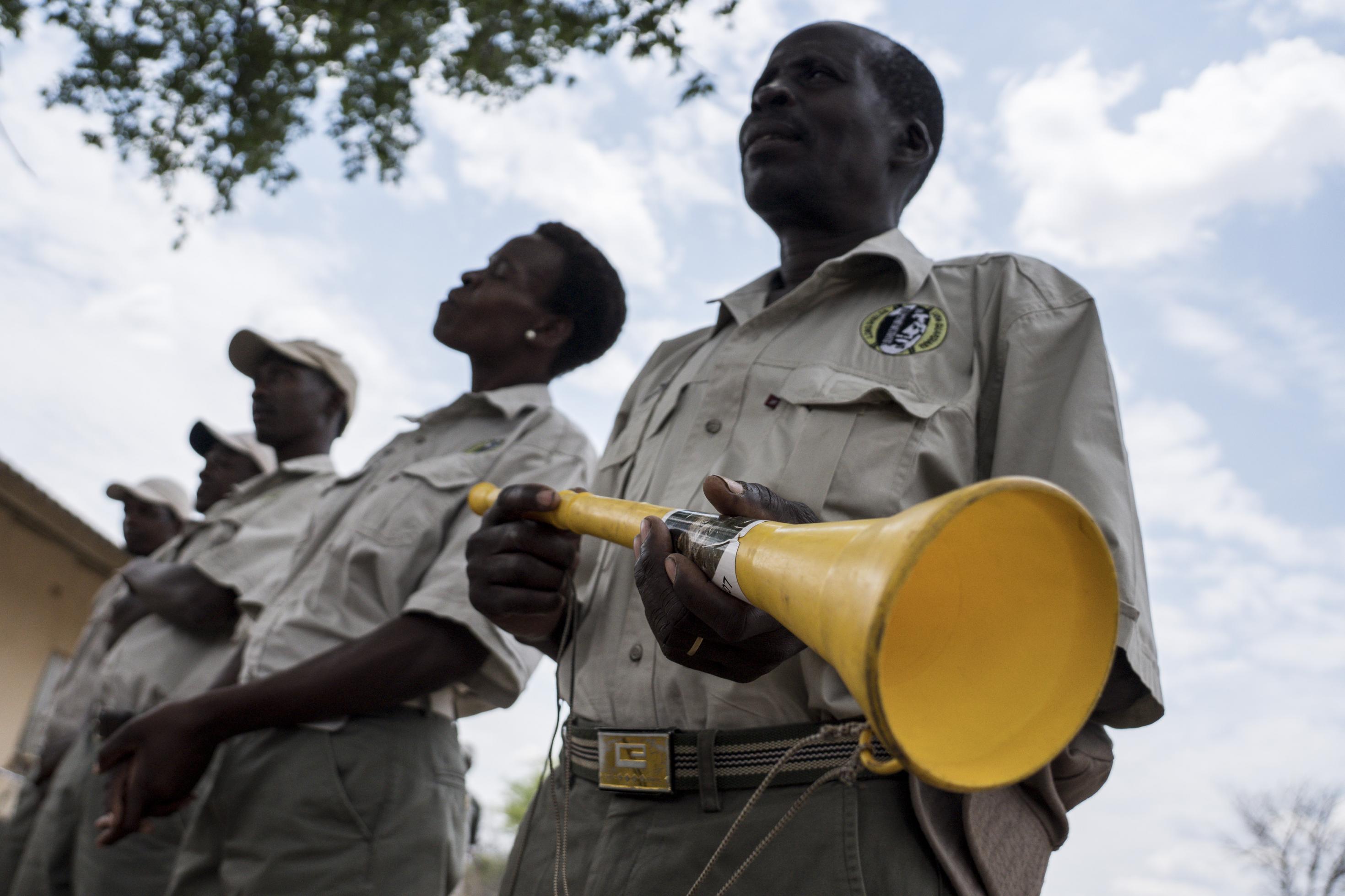 Die Lion Guardians stehen in einer Reihe, der Mann im Vordergrund hält eine Vuvuzela, eine gelbe Plastiktröte in den Händen