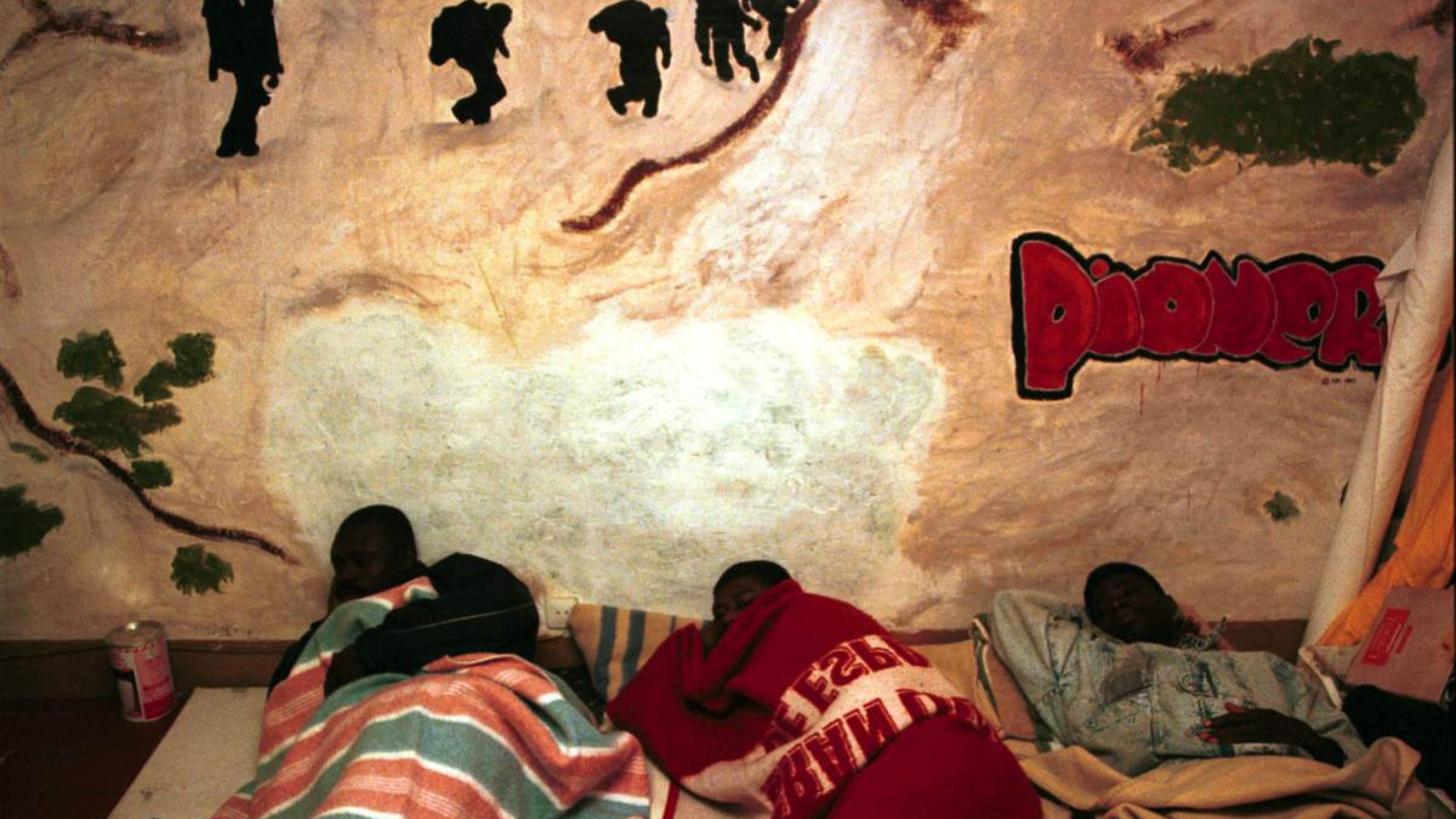 Migranten schlafen in einer als Unterkunft hergerichteten Wohnung in Barcelona am Boden.