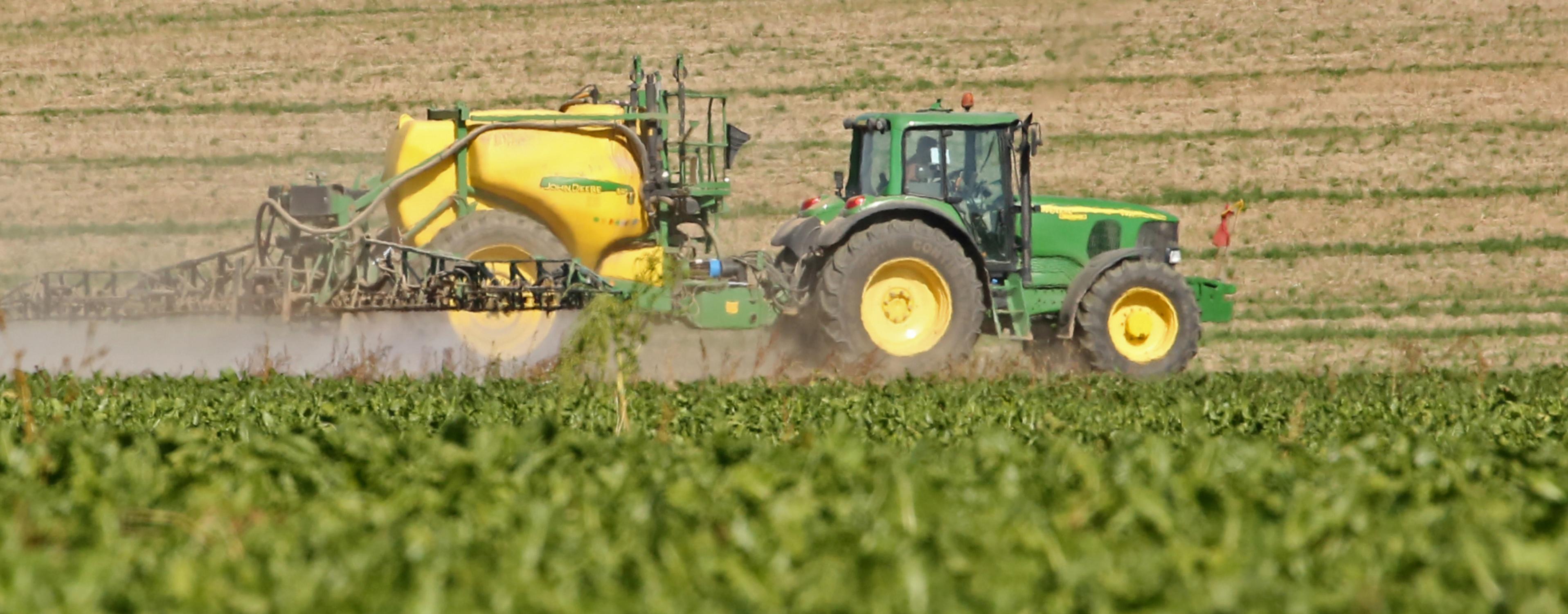 Ein Traktor spritzt Chemikalien auf einen Acker