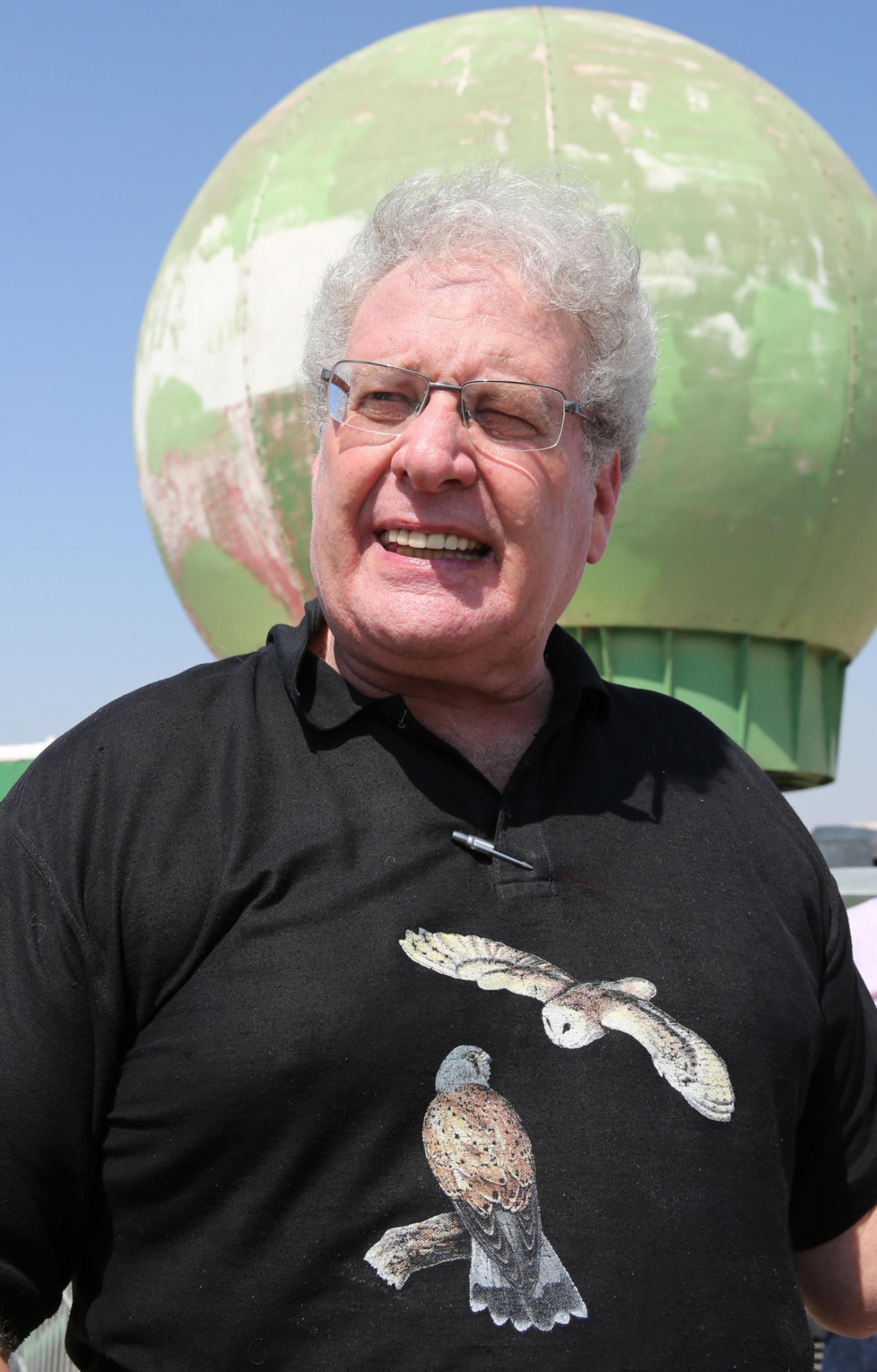 Yossi Leshem steht mit einem Thomas-Shirt mit Schleiereulen vor einem Radar zur Zugvogelforschung.