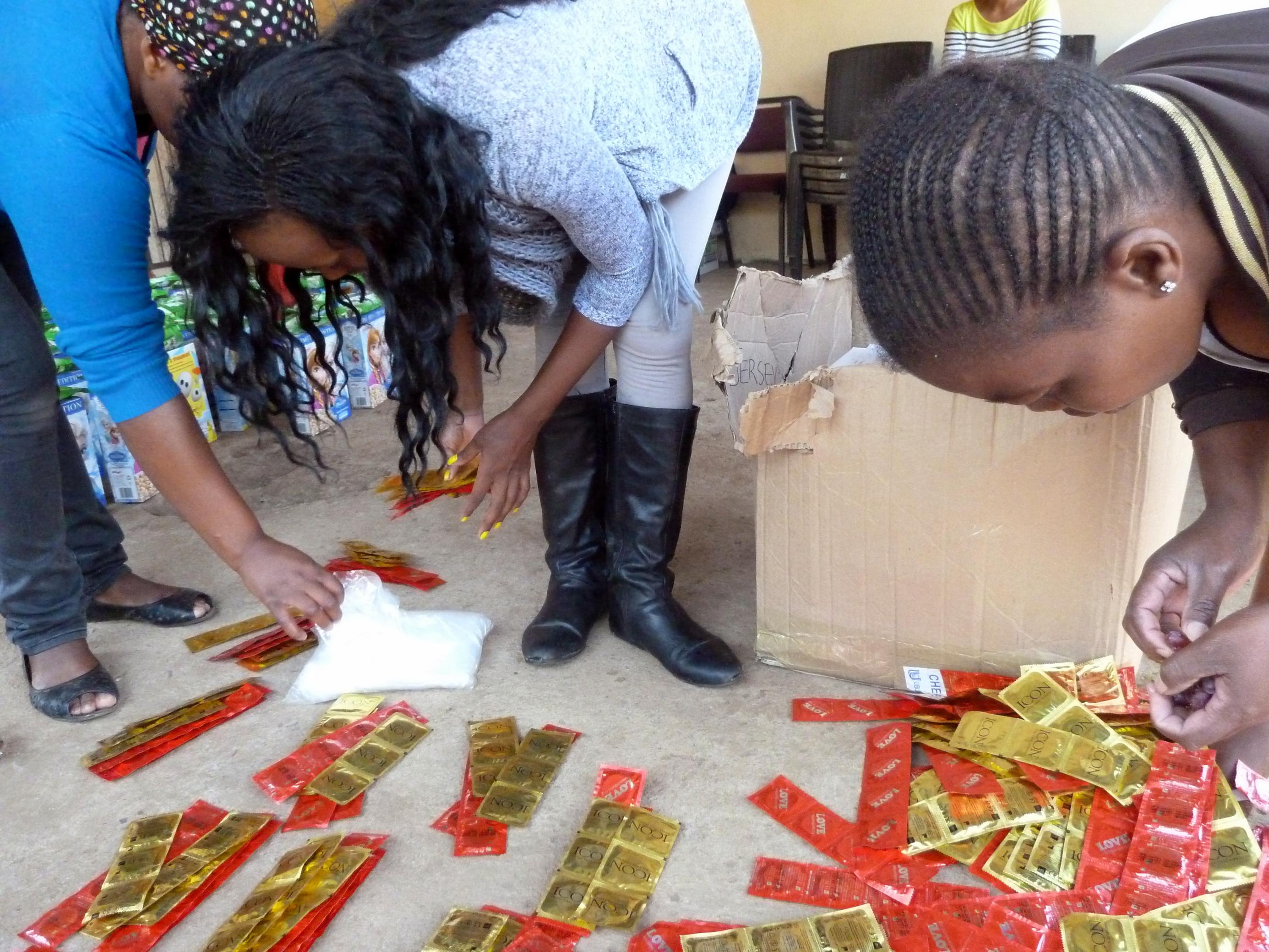 Aktivistinnen beugen sich über verpackte Kondome, die auf dem Boden liegen, um sie für die Verteilung zurechtzulegen.