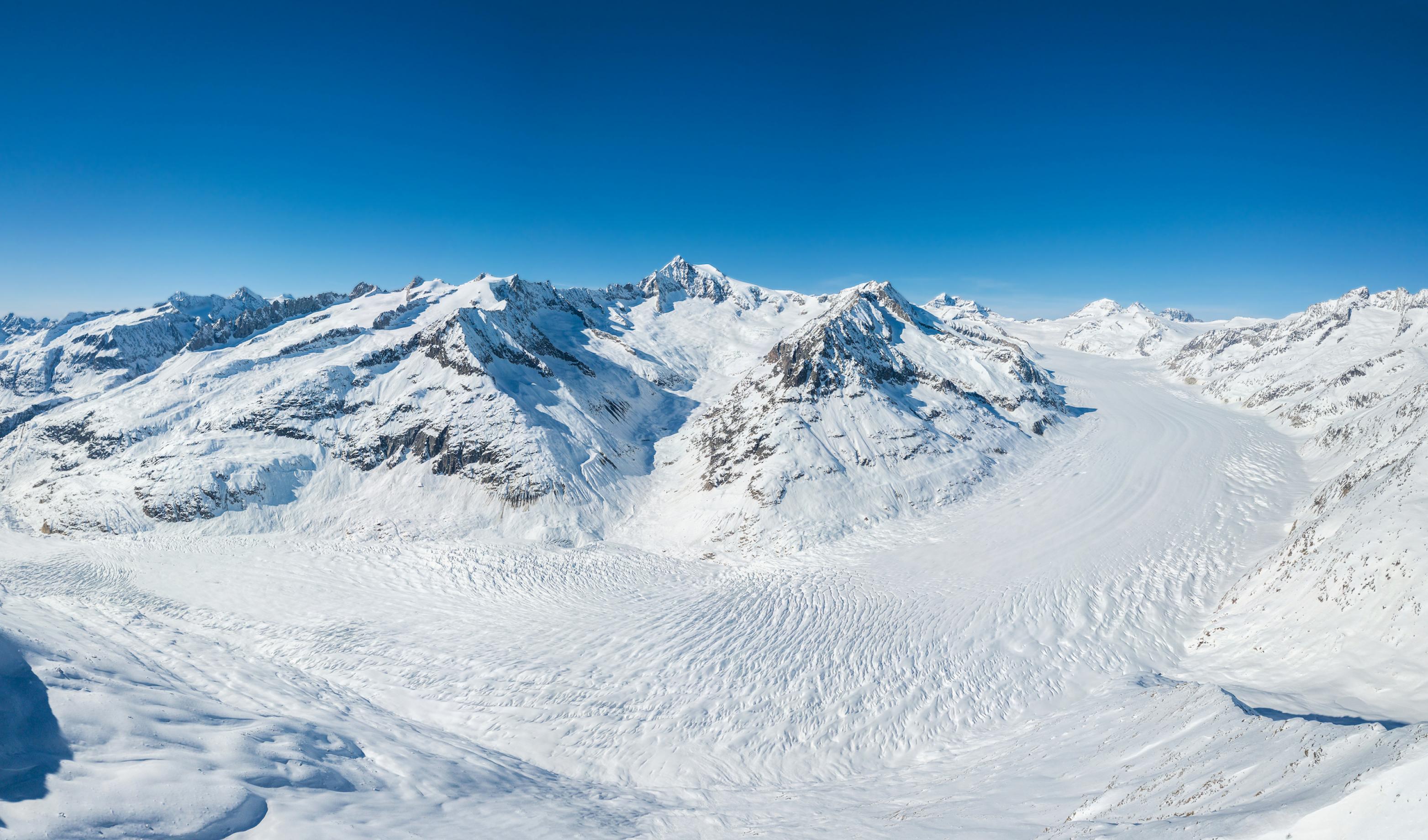 Hochgebirgslandschaft mit dem breiten Gletscherstrom im Winter bei blauem Himmel.