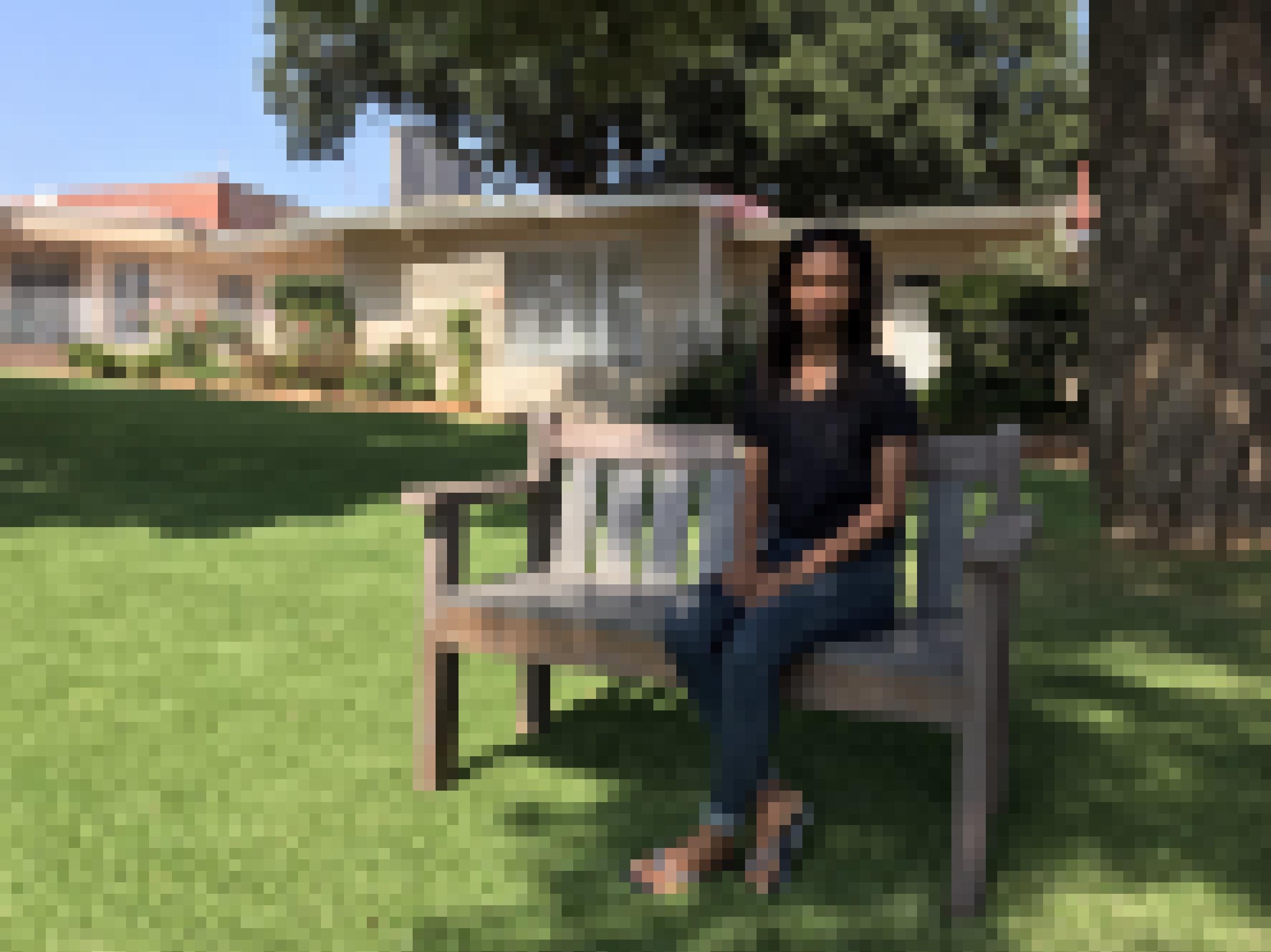 Die Gartenbank, auf der die junge Frau sitzt, steht unter einem Baum vor dem deutschen Altersheim in Johannesburg.