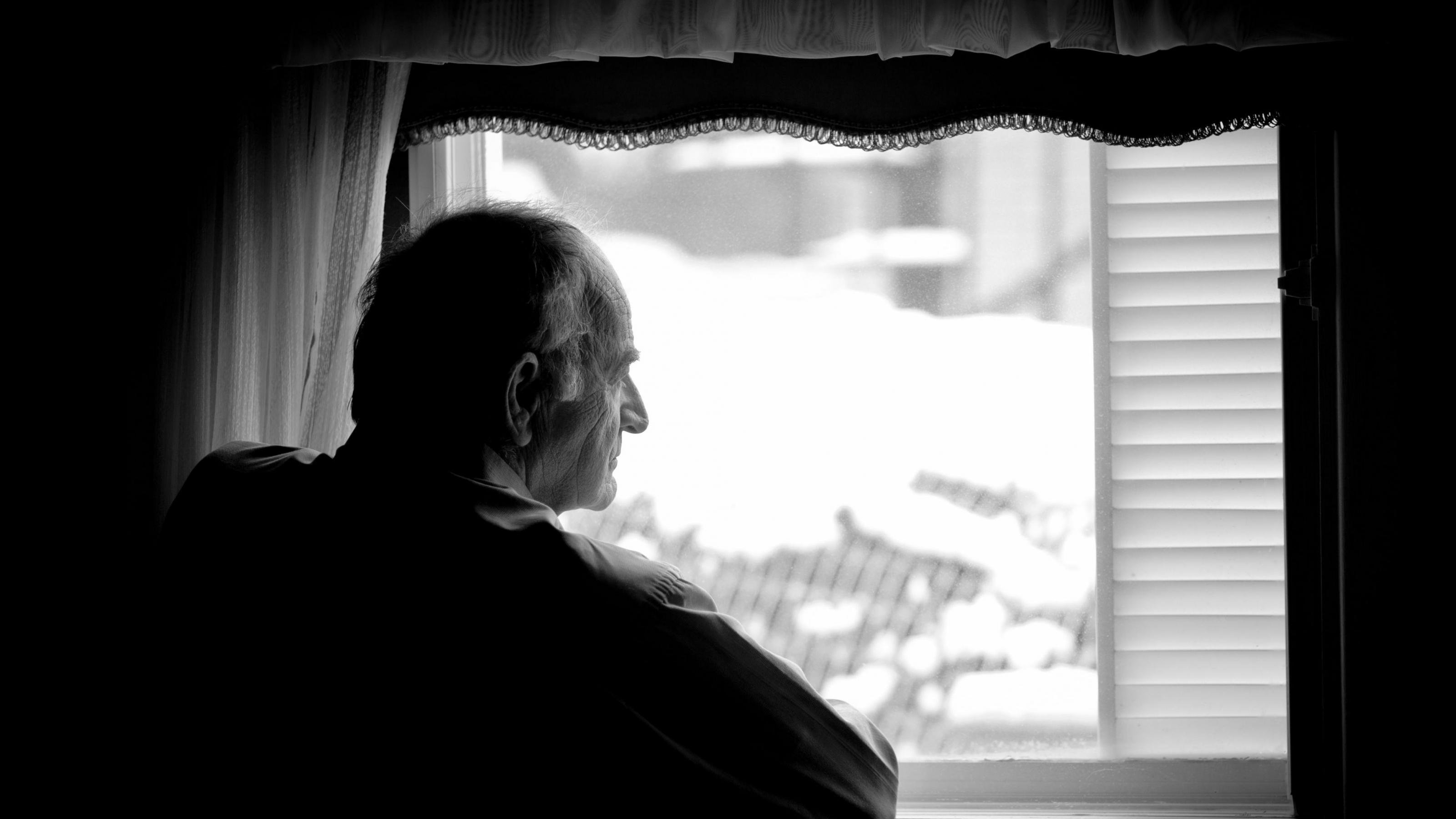 Alter Mann schaut aus dem Fenster. Während der Corona-Pandemie bedeutet Schutz oft Isolation der Risikogruppen.
