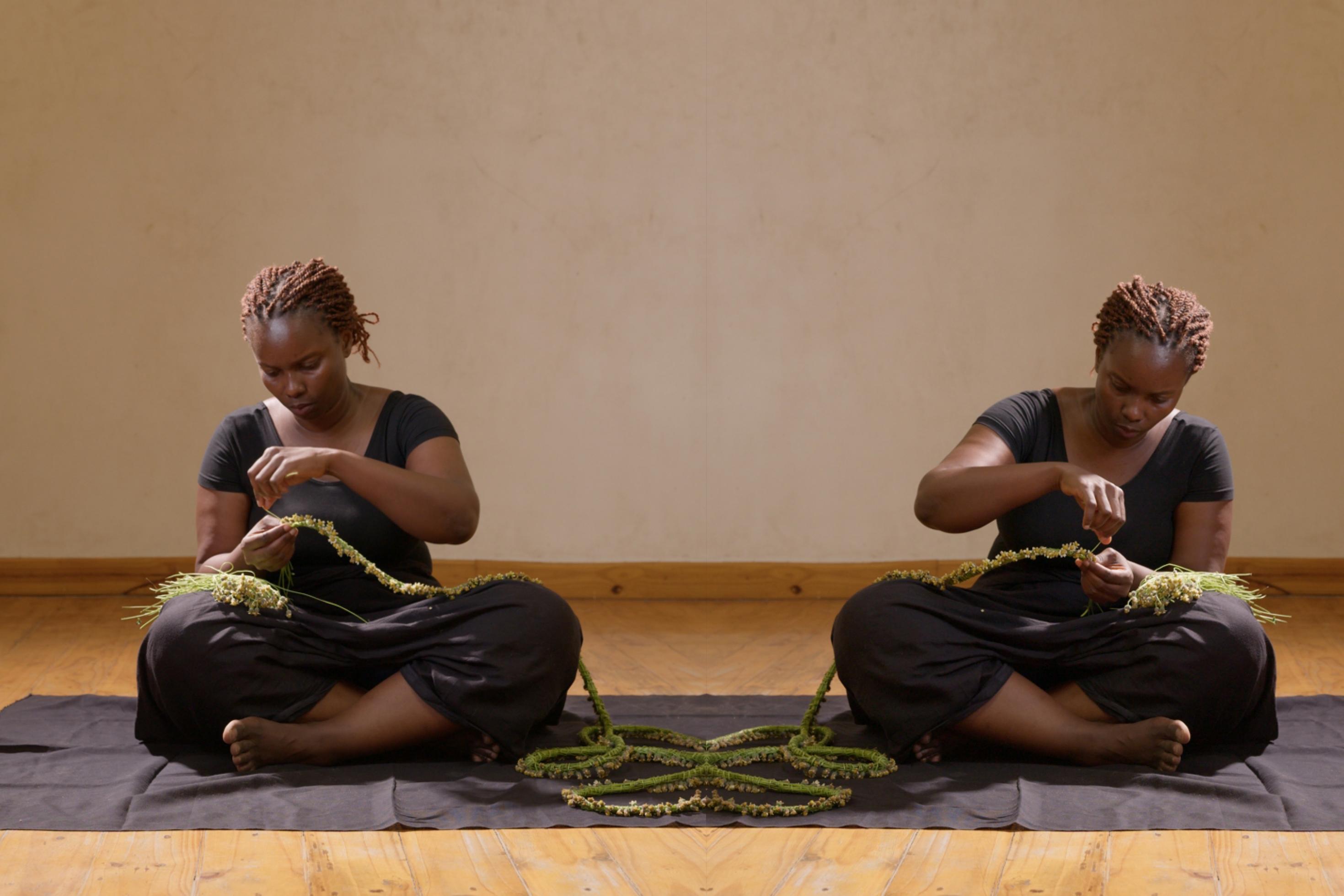 Gespiegeltes Motiv: Eine junge Frau aus Tansania sitzt auf dem Boden und webt ein Band aus Blumen.
