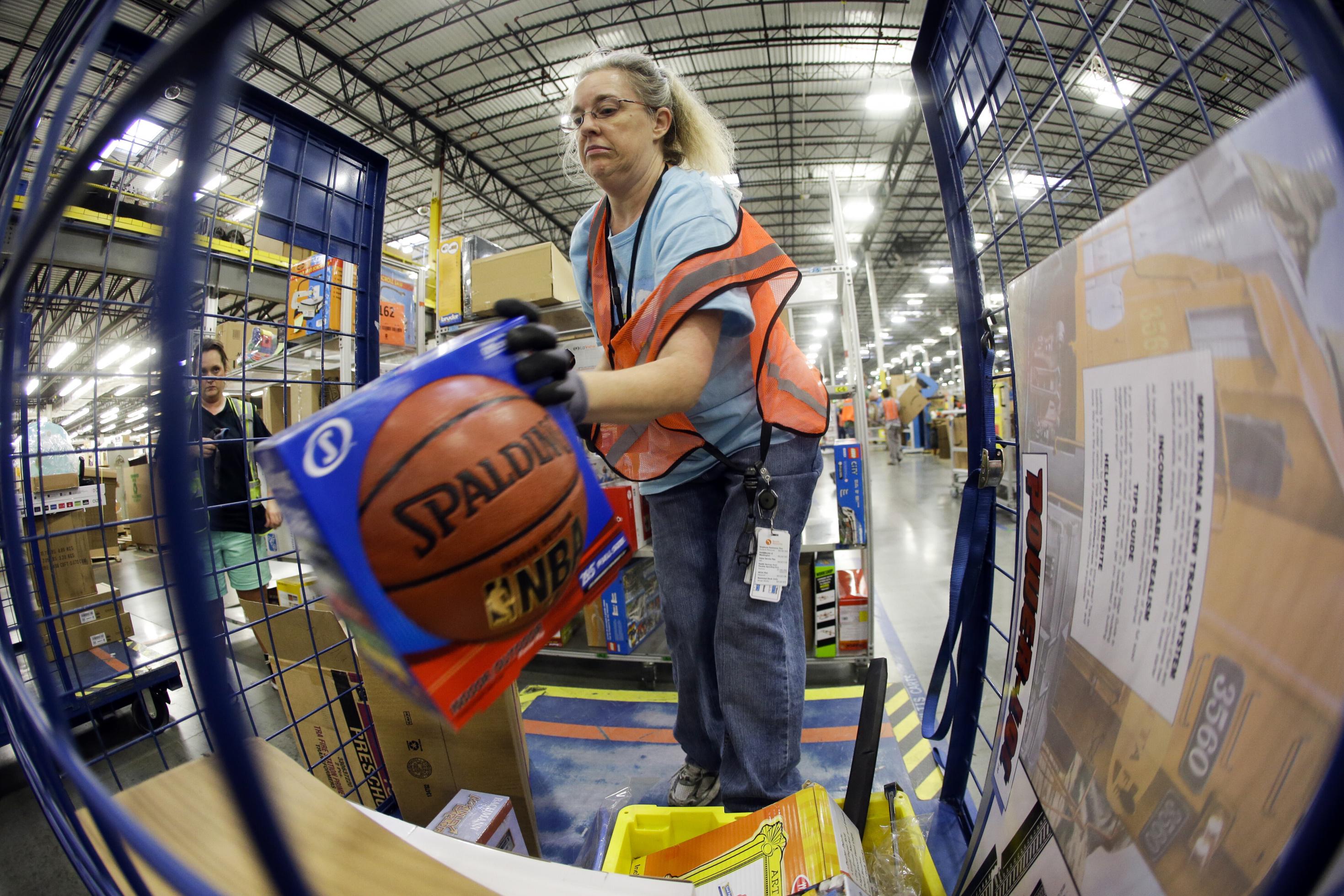 Das Foto zeigt eine ältere Frau mit orangefarbener Warnweste, die einen Basketball in einen Transportkarren legt,