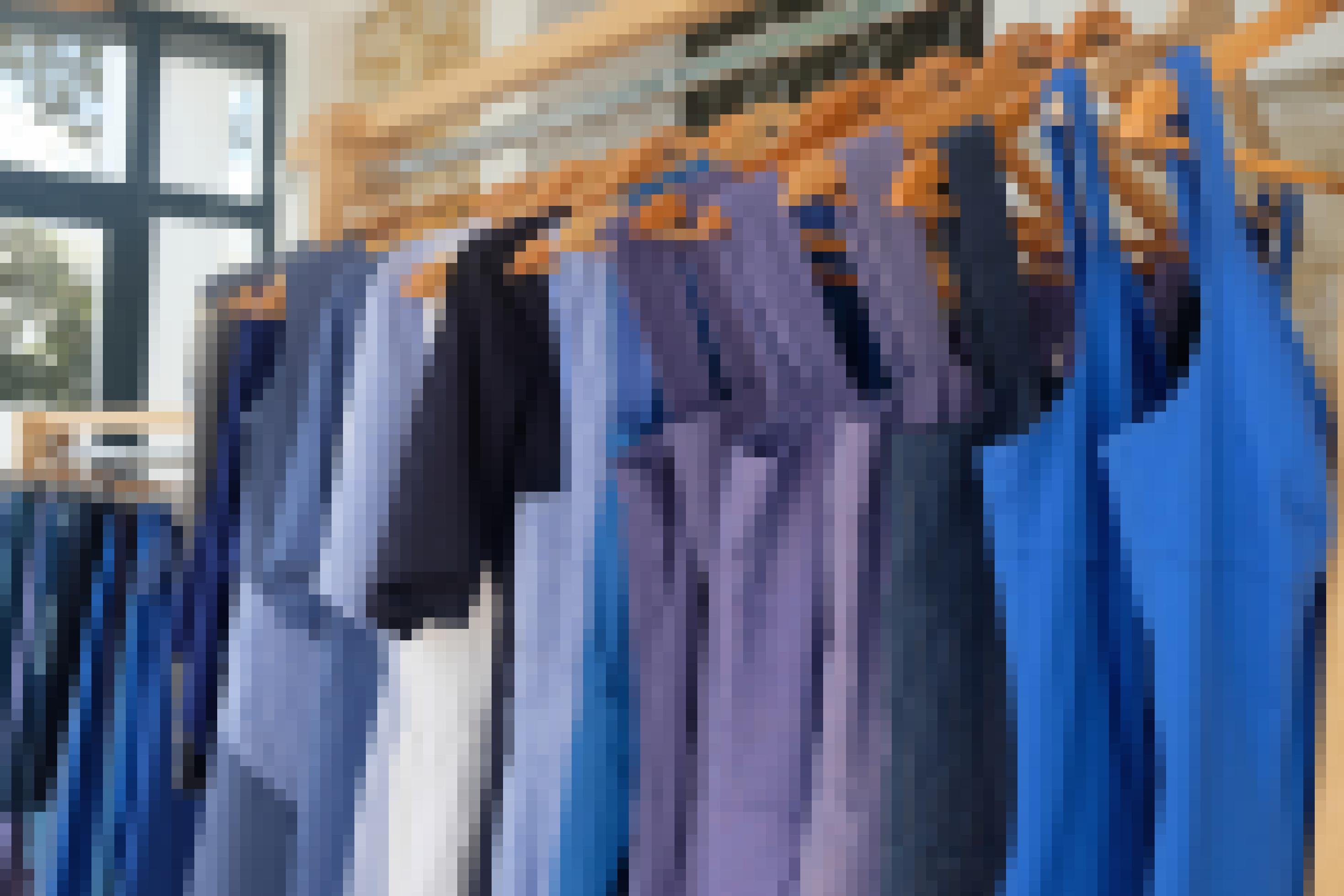 Eine Reihe blauer Jumpsuits hängt an einer Kleiderstange