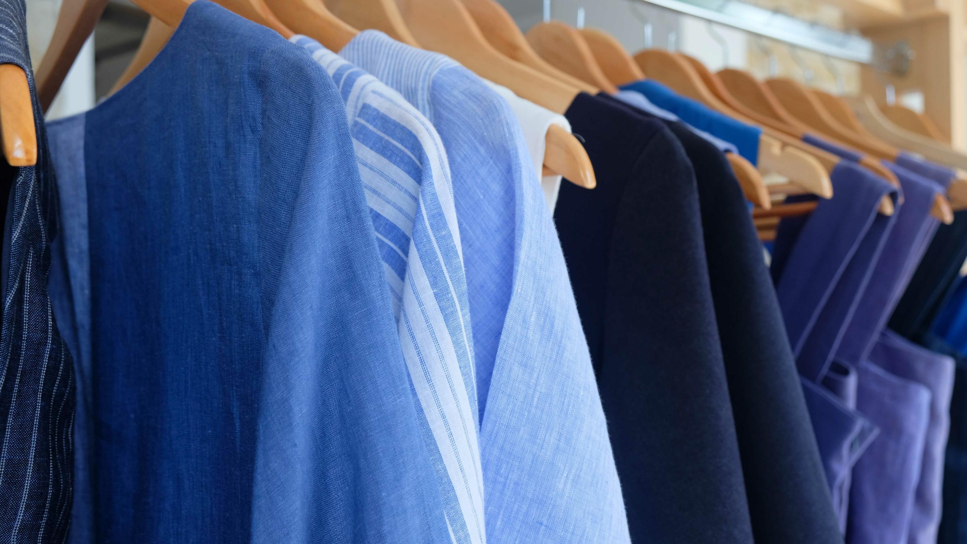 Kleidung in verschiedenen Blautönen hängt auf einer Stange