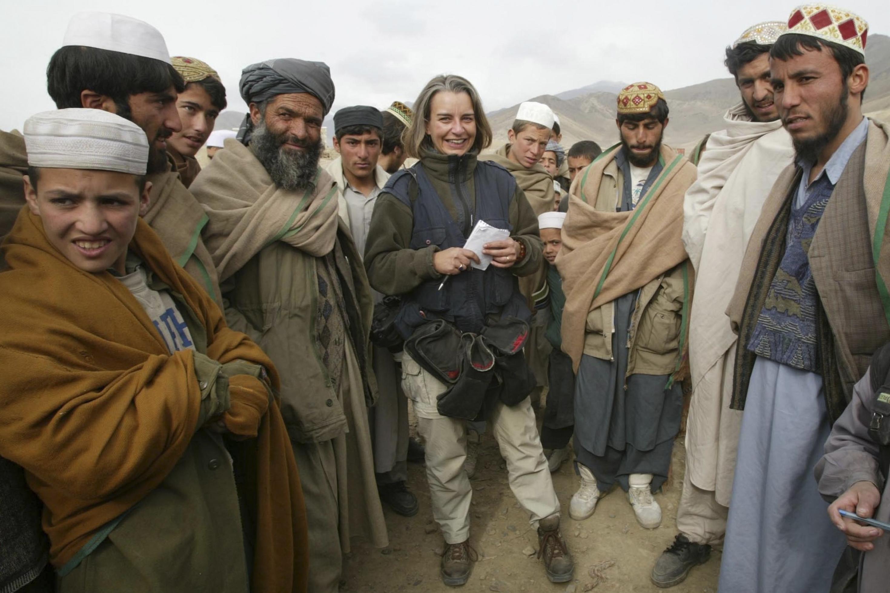 Eine freundlich lächelnde Reporterin steht umringt von afghanischen Männern.