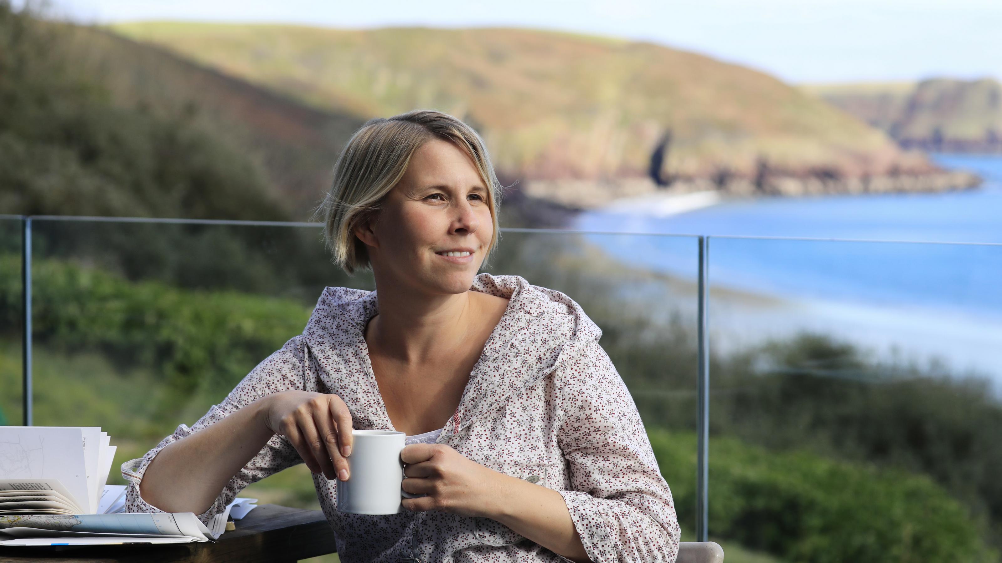 Anne Preger sitzt mit einem Becher in der Hand auf einer Terrasse.