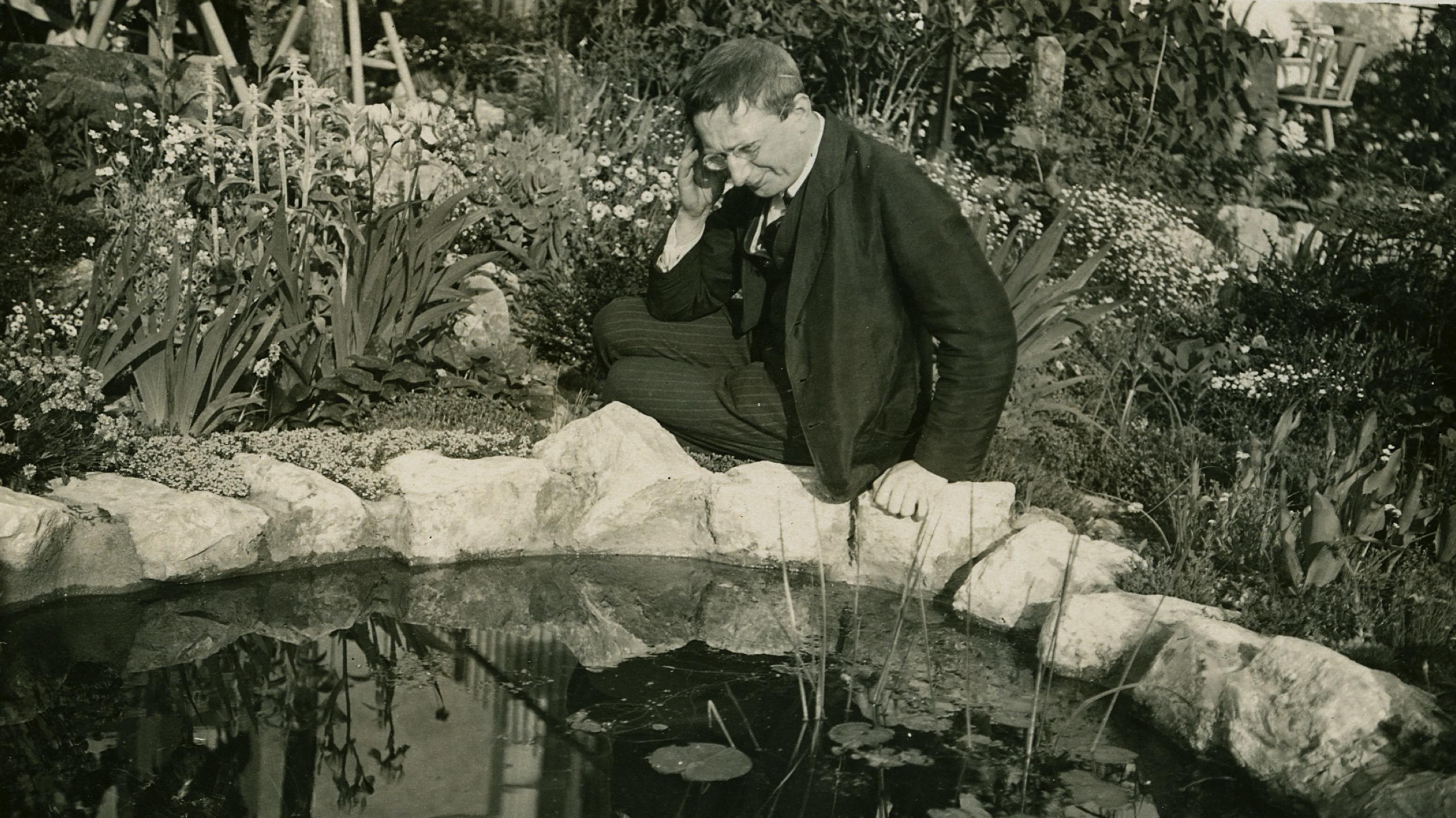 Der Schriftsteller Alfred Döblin sitzt an einem Brunnen.
