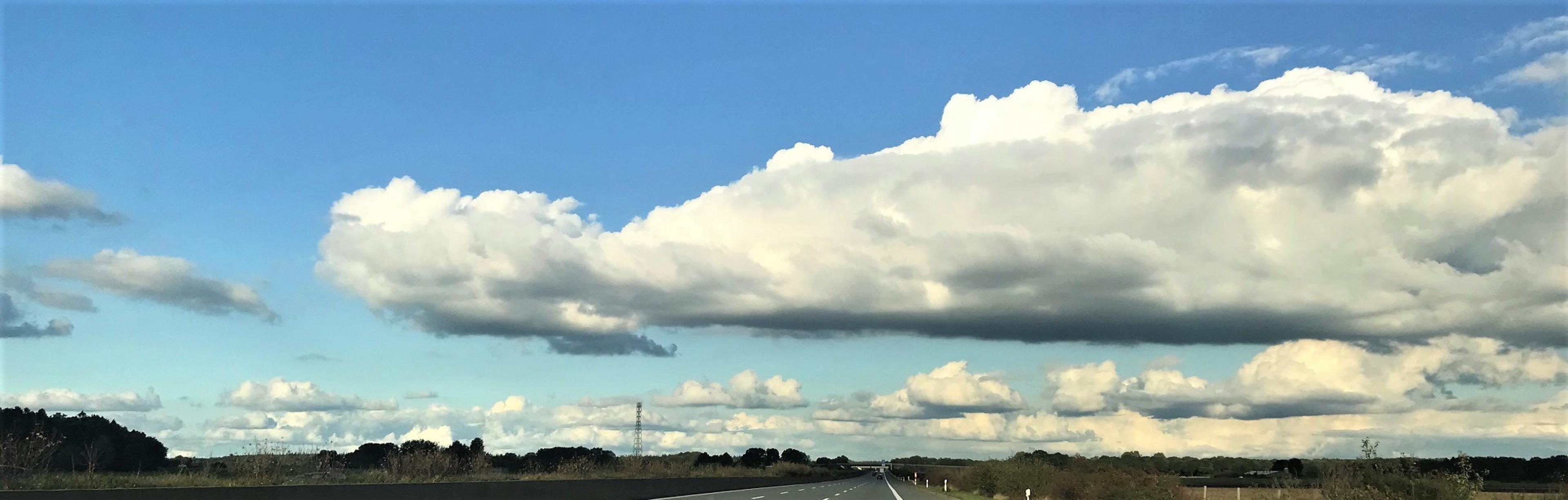 Über eine Landstraße ziehen Wolken hinweg.