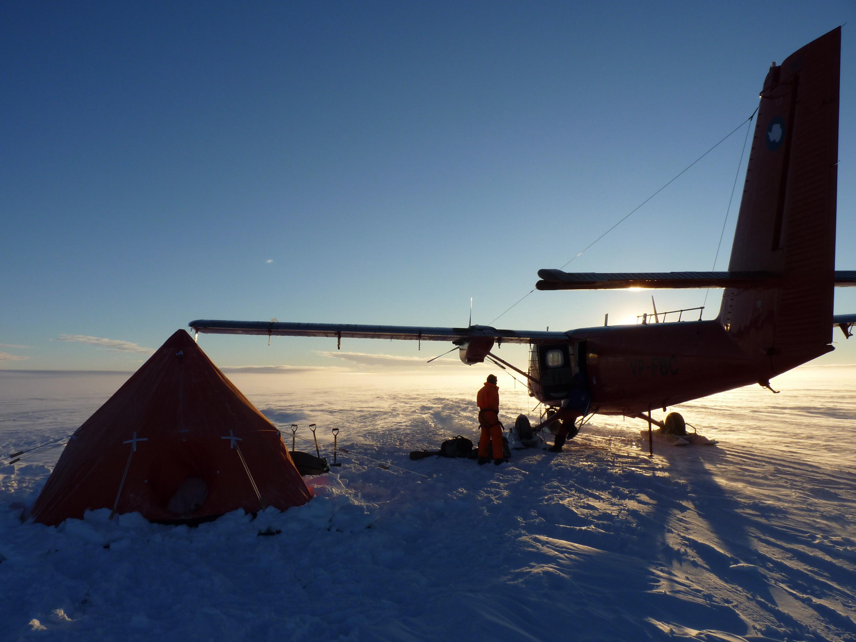 Flugzeug neben einer Forschungsstation im Eis der Antarktis
