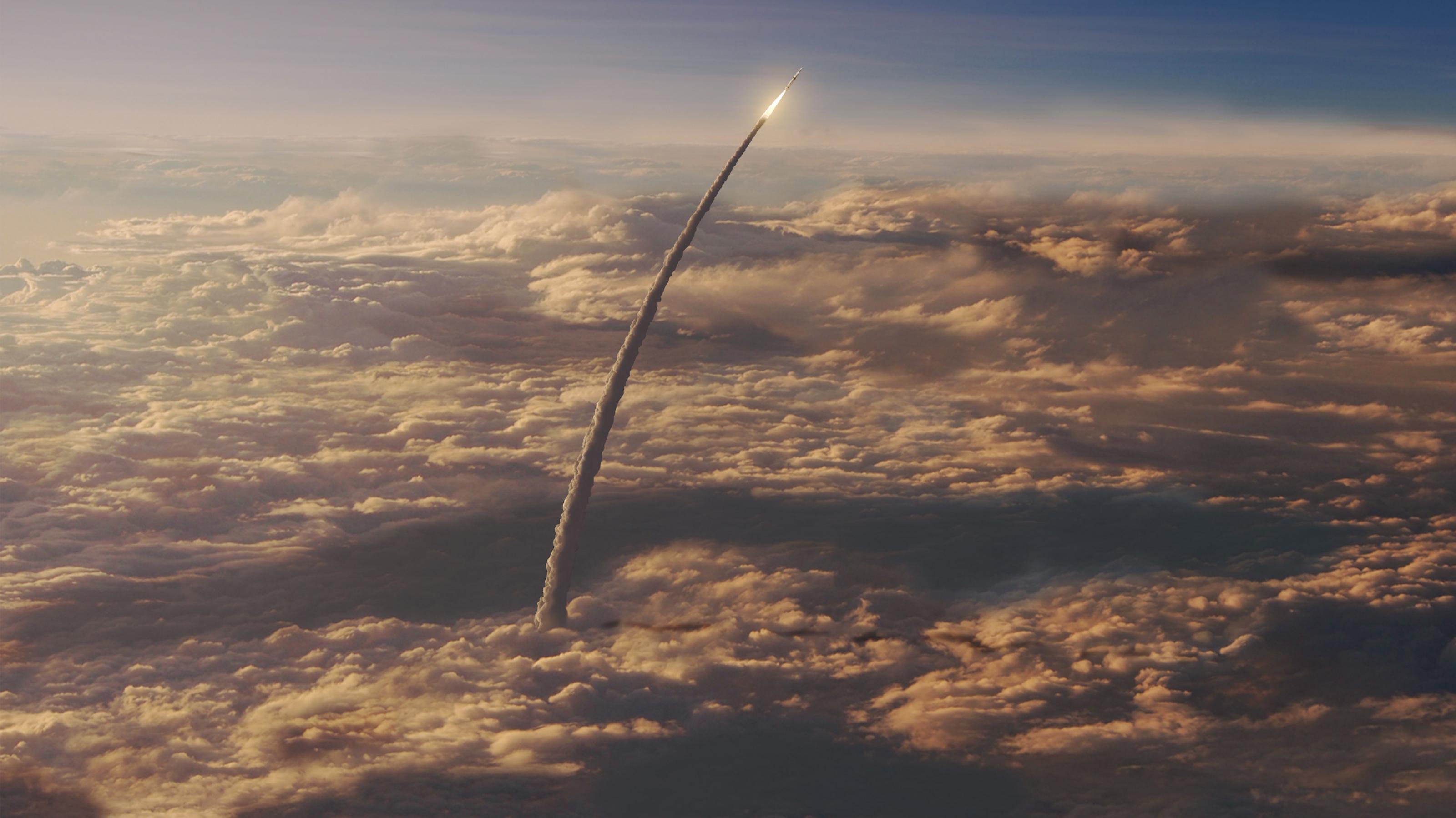 Eine Rakete fliegt über der Wolkendecke weiter Richtung Himmel.