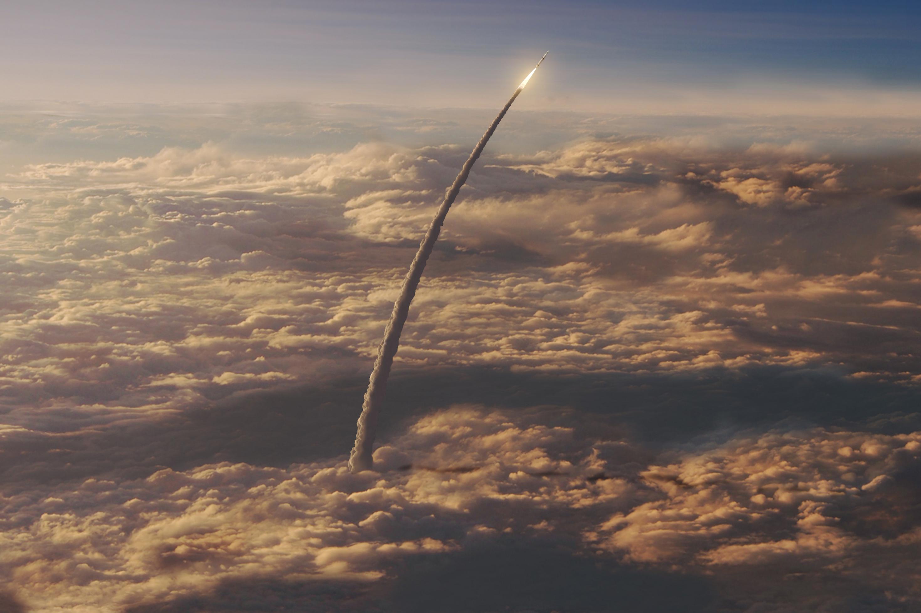 Eine Rakete fliegt über der Wolkendecke weiter Richtung Himmel.