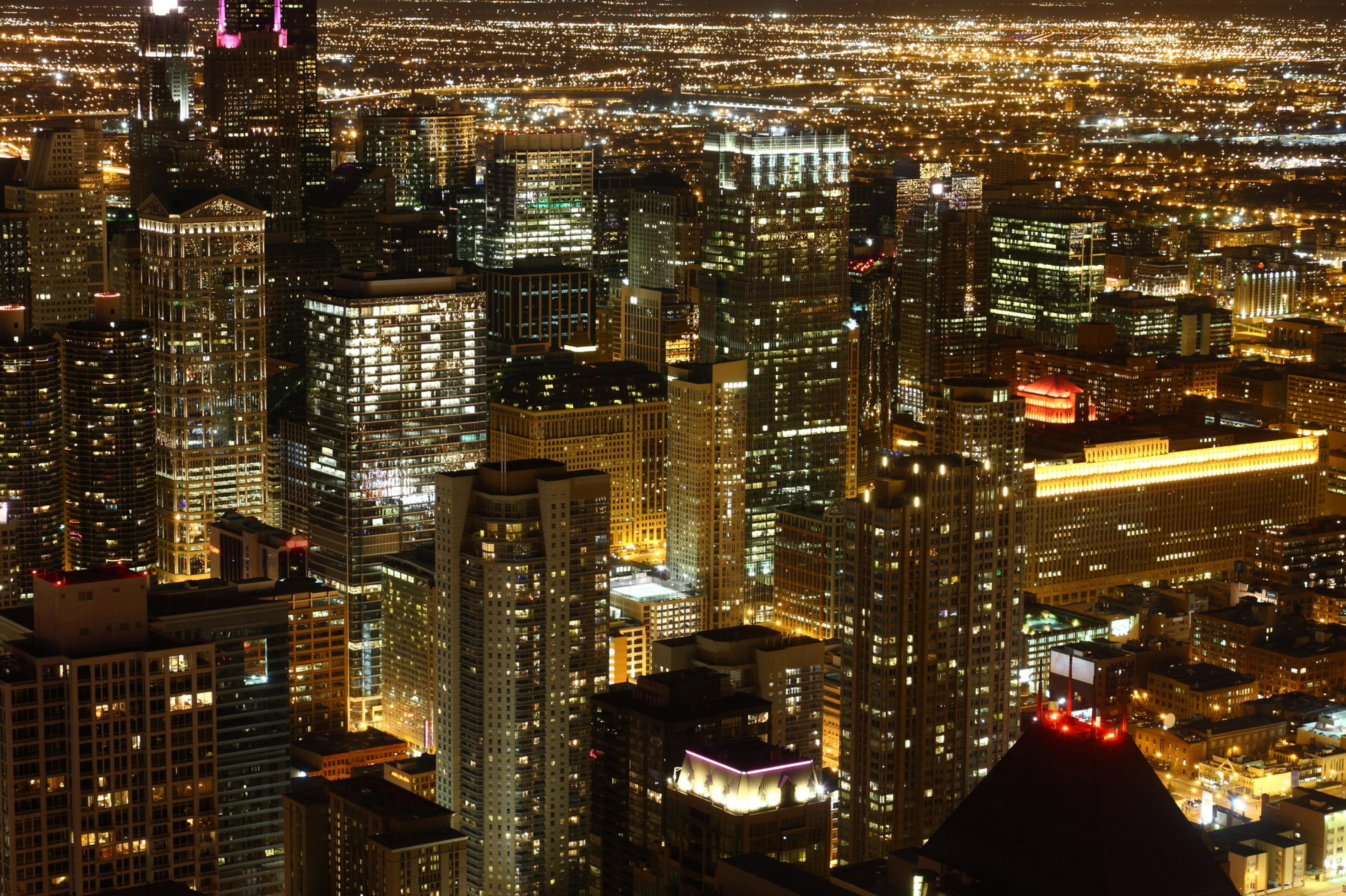 Das Bild zeigt die Innenstadt von Chicago mit zahlreichen Wolkenkratzern und greller Beleuchtung bei Nacht.