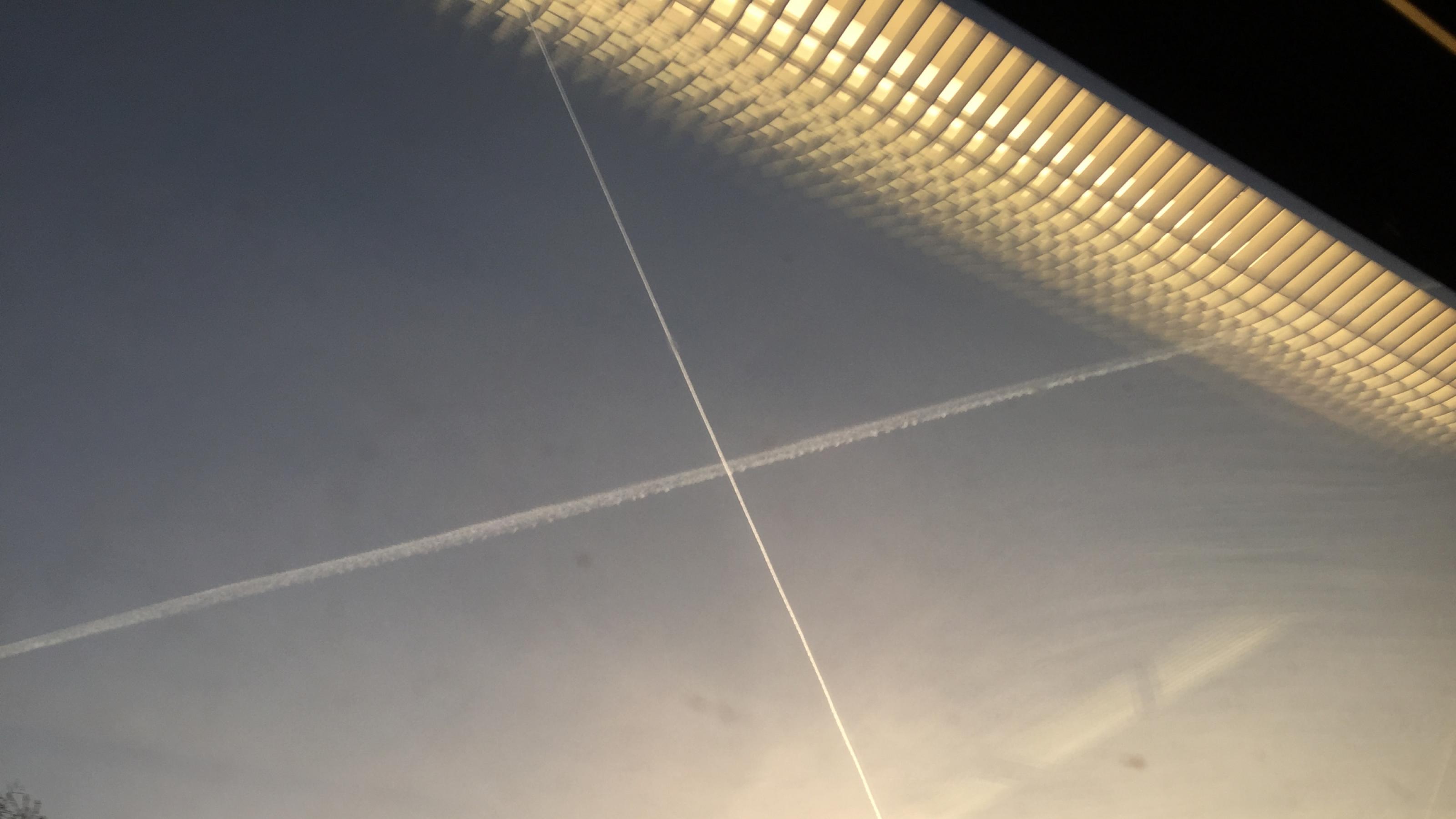 Kondensstreifen am Himmel durch ein Fenster fotografiert