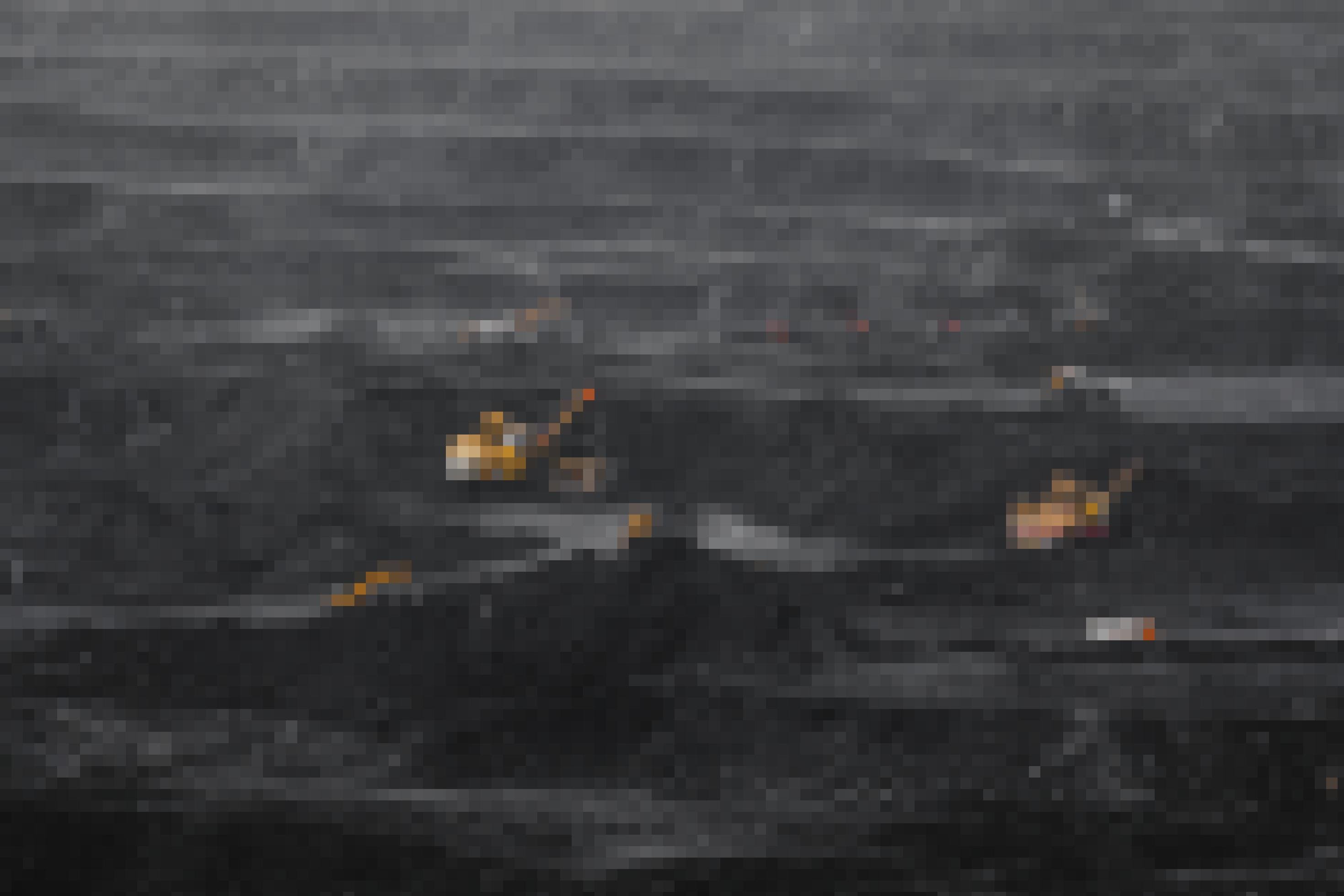 Schwarze Kohlebergbaulandschaft mit klein wirkenden orangefarbenen Baggern