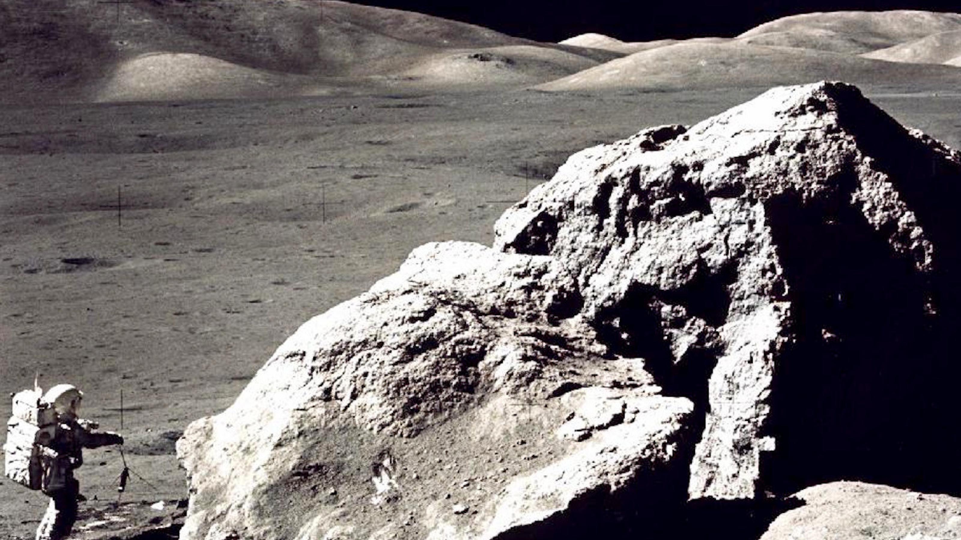 Auf dem Mond: ein hausgroßer Fels, daneben ein Astronaut im Raumanzug