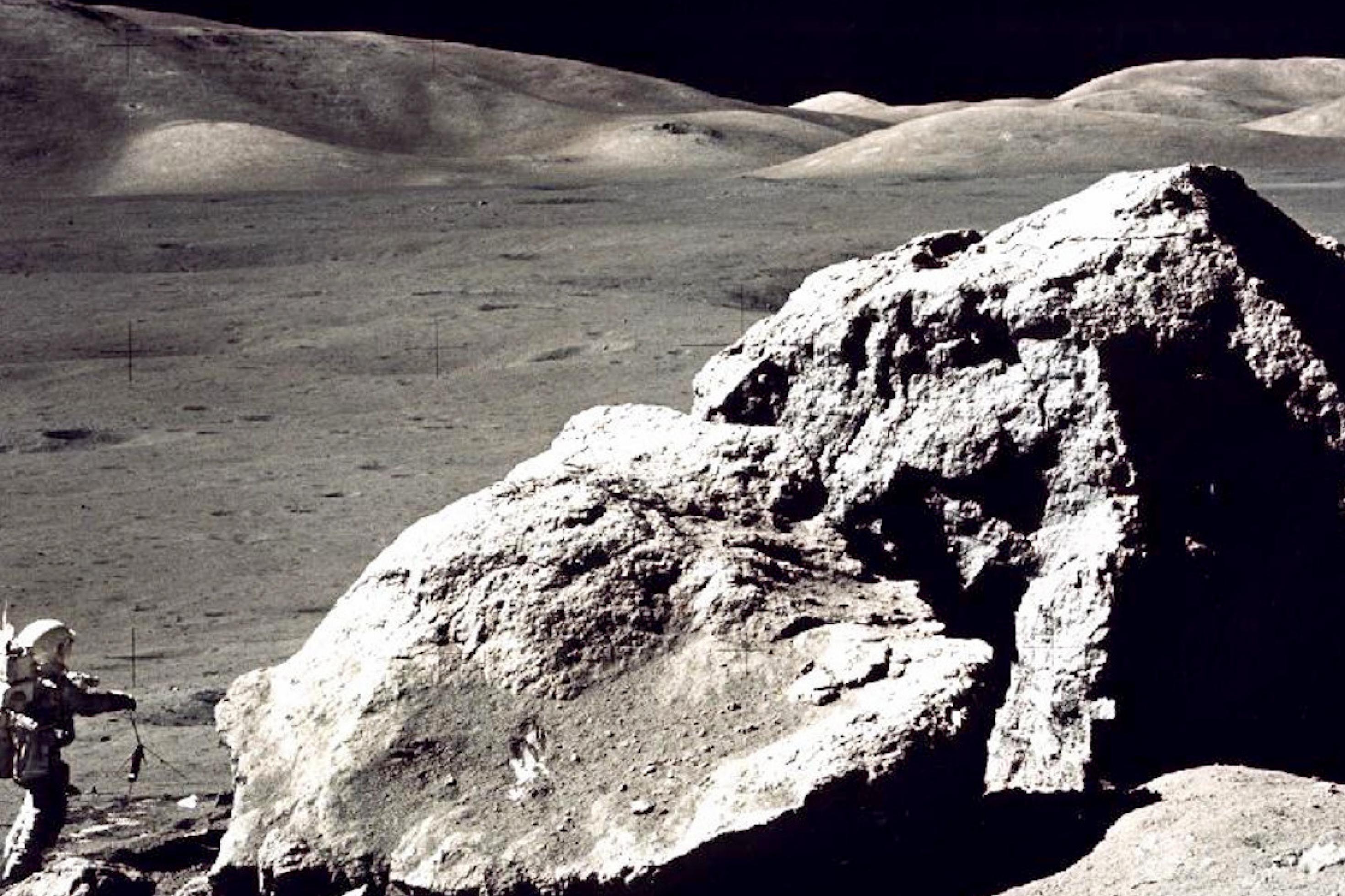 Auf dem Mond: ein hausgroßer Fels, daneben ein Astronaut im Raumanzug