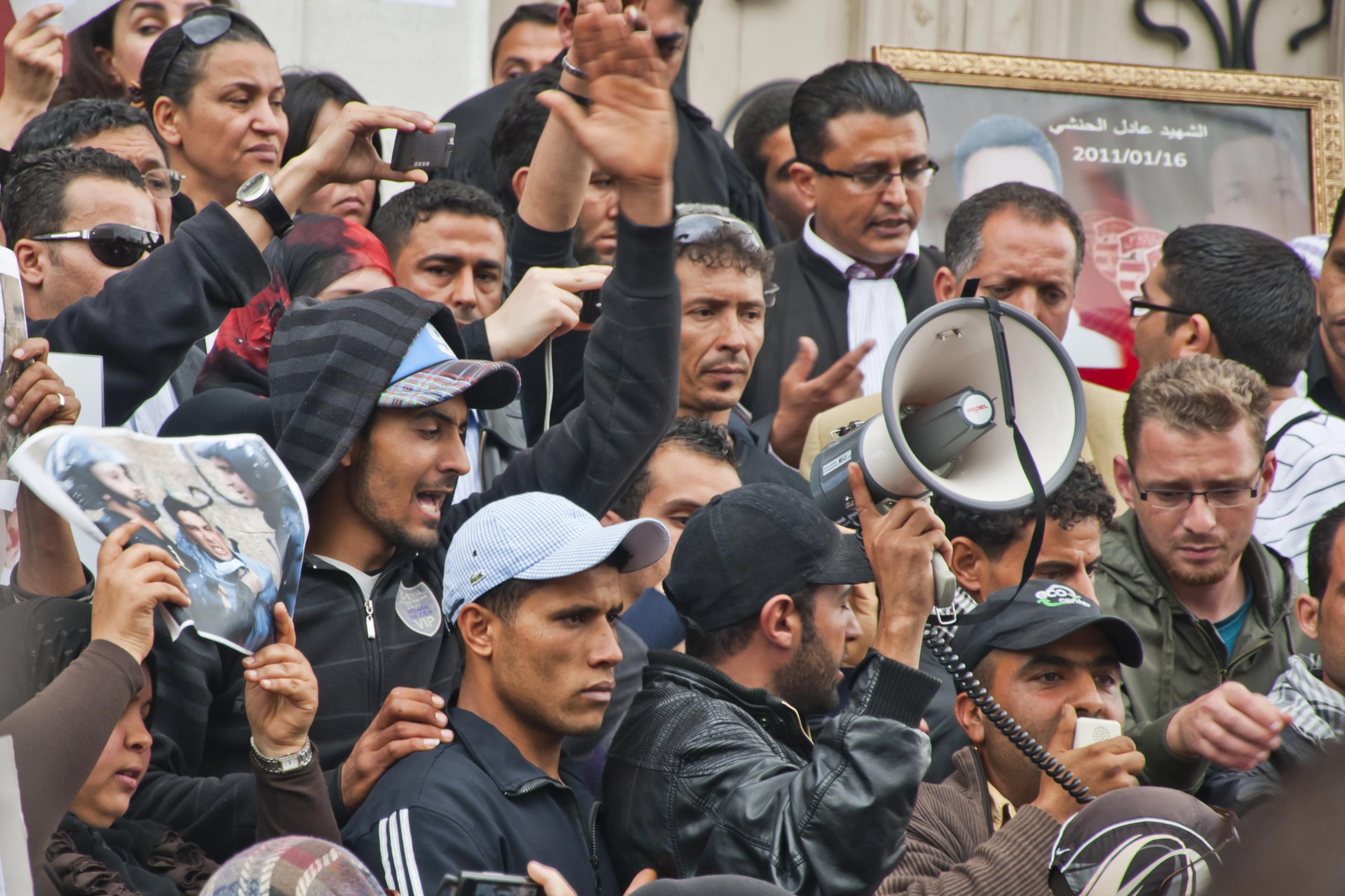 Gruppe von zumeist dunkelhäutigen Männern, die auf einer Treppe stehen, darunter ein Mann mit einem Megaphon.
