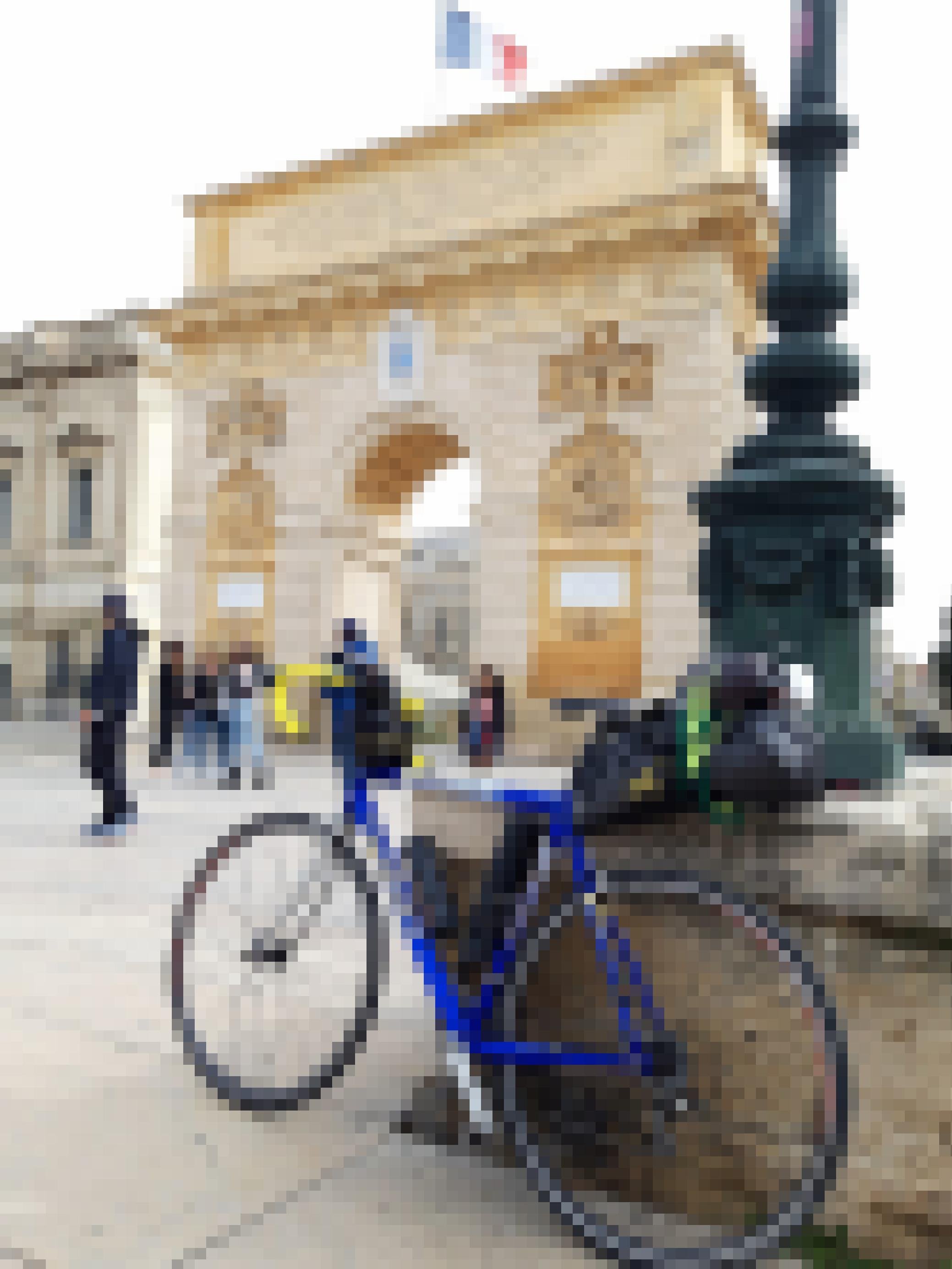 Das bepackte Rennrad lehnt an einer Mauer vor Montpelliers Triumphbogen.