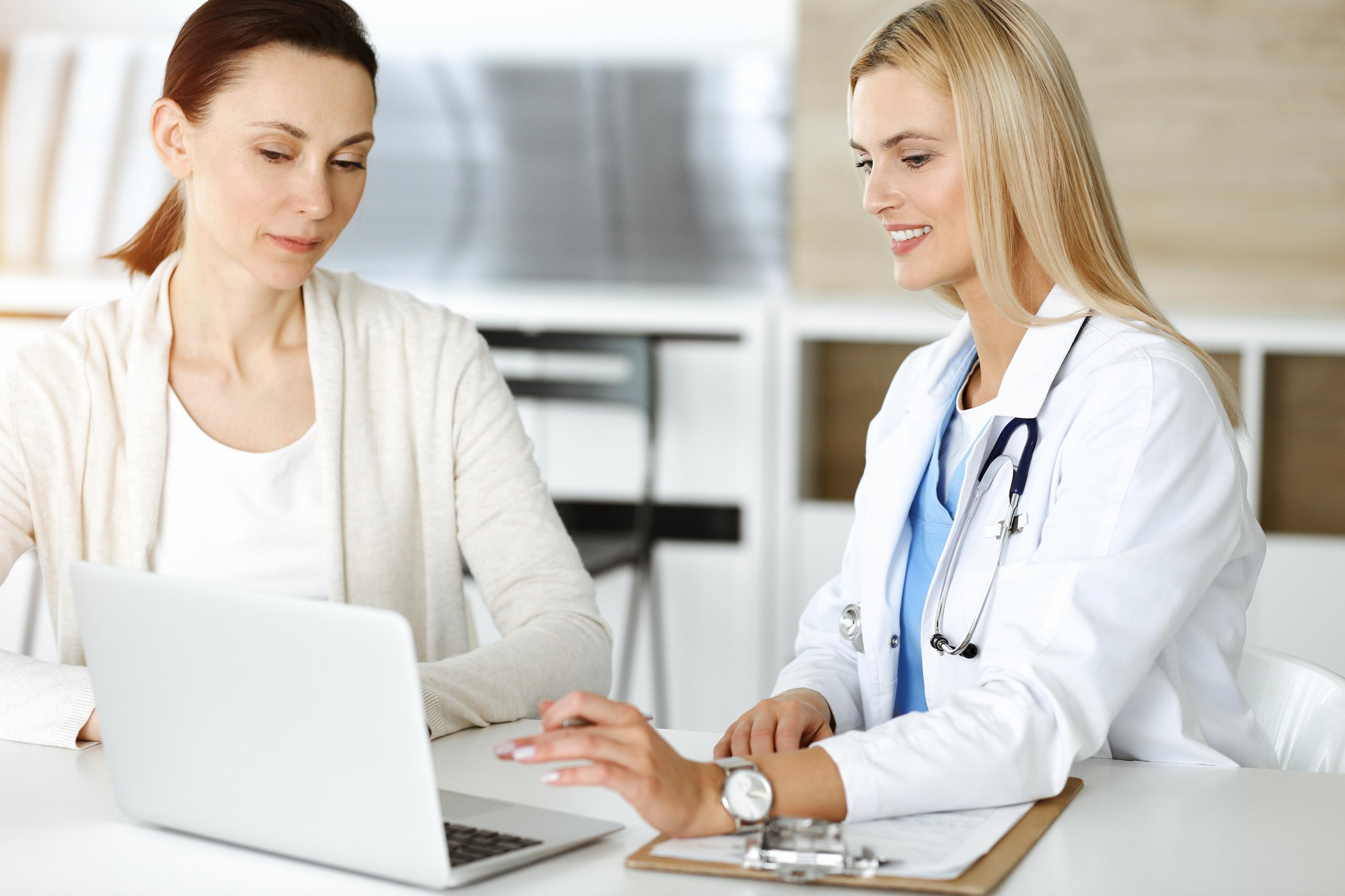 Eine Ärztin zeigt ihrer Patientin den Bildschirm ihres Laptops.