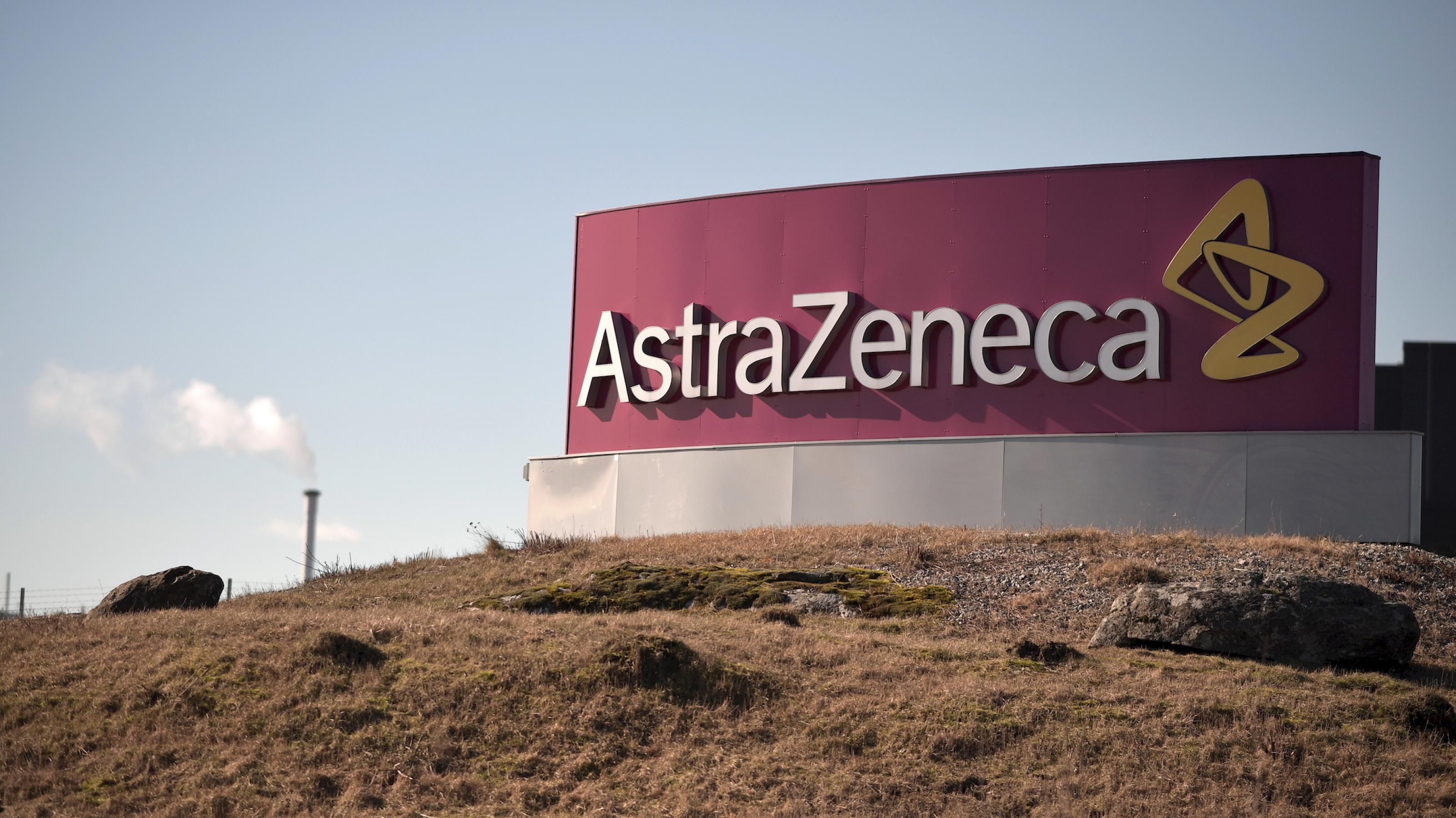Das Logo von AstraZeneca vor einer Landschaft mit brauner Erde.