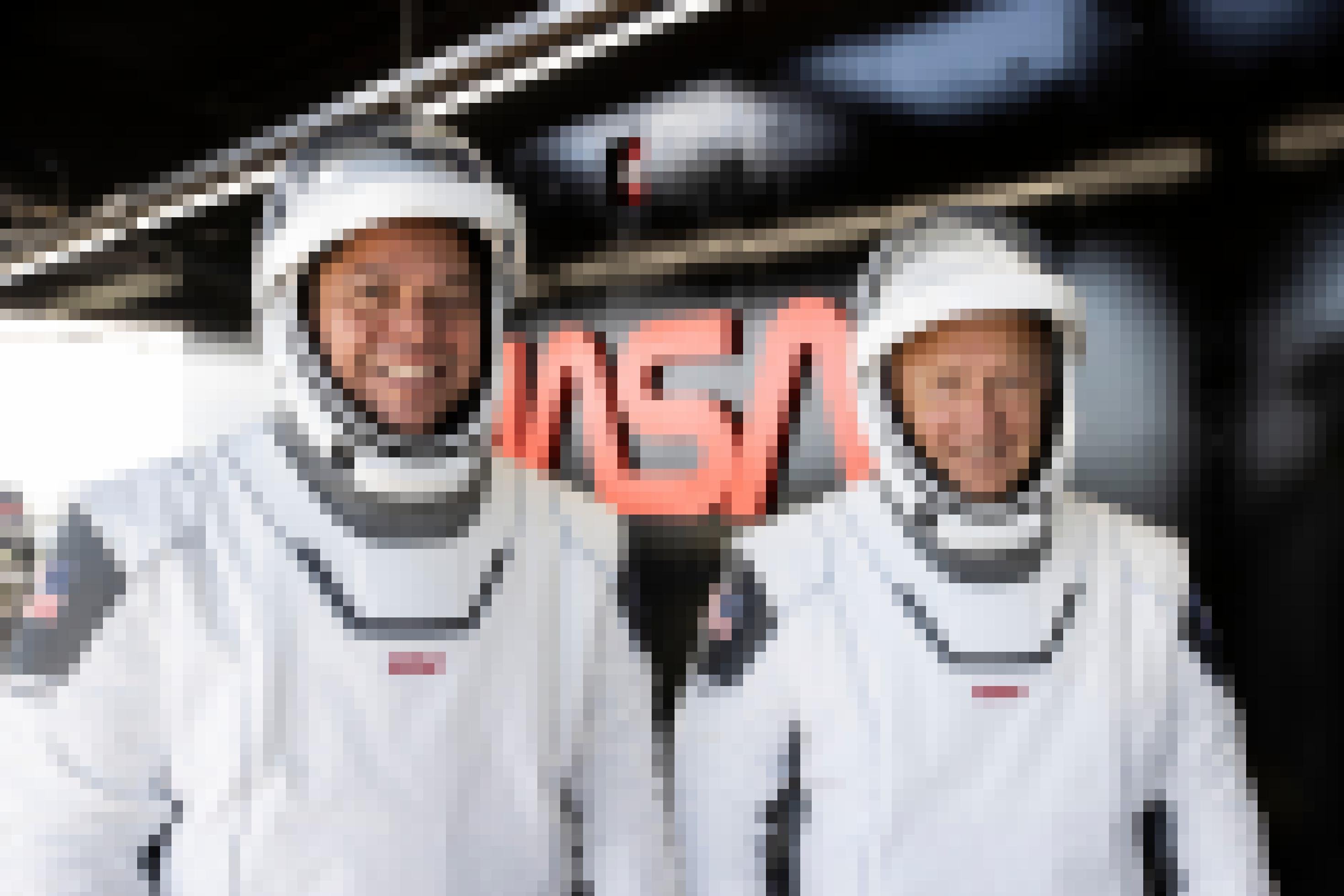 Astronauten Douglas Hurley und Robert Behnken im Raumanzug vor einem NASA-Schriftzug